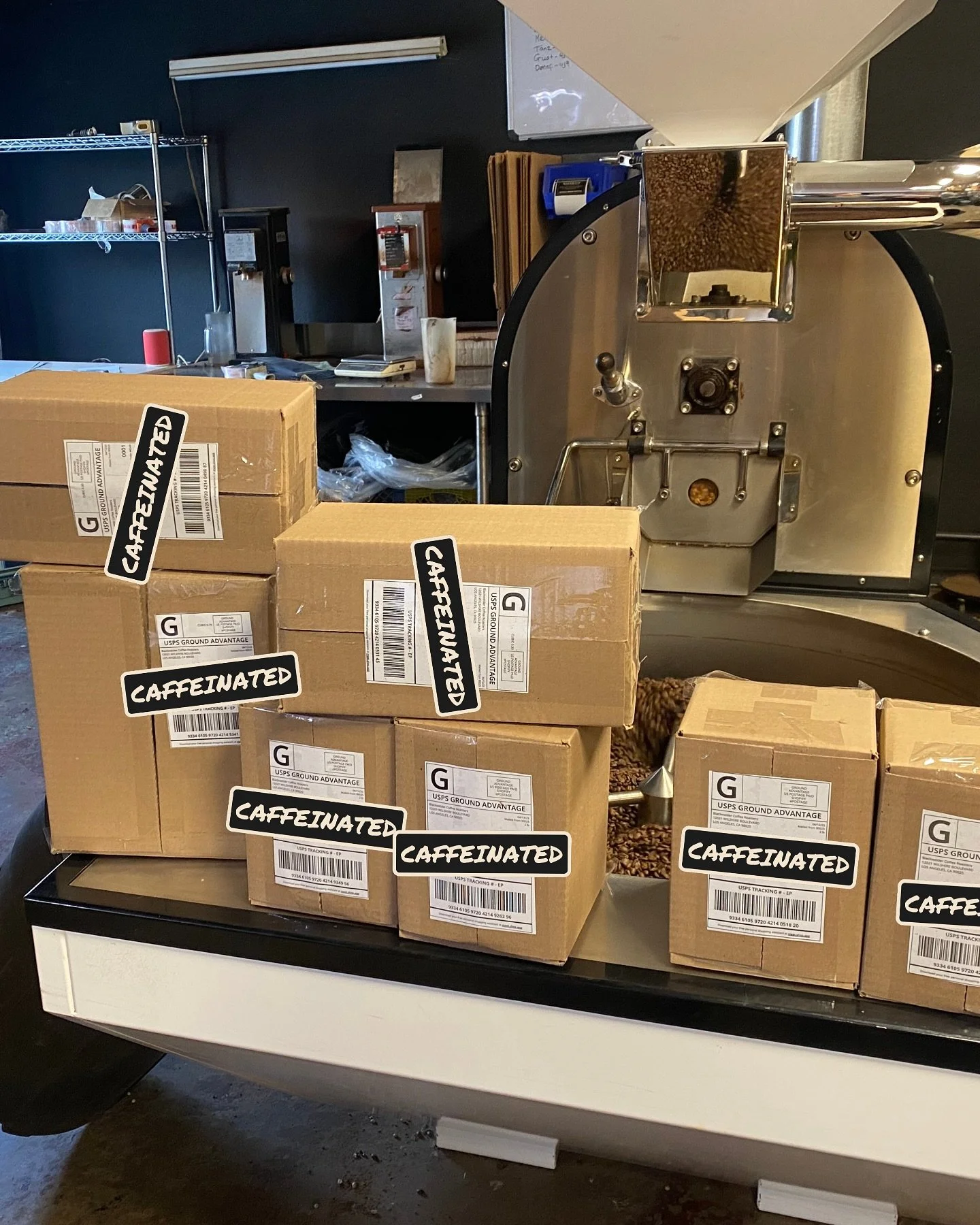 Boxes of caffeinated coffee beans on a checkout counter, with a coffee grinder in the background.