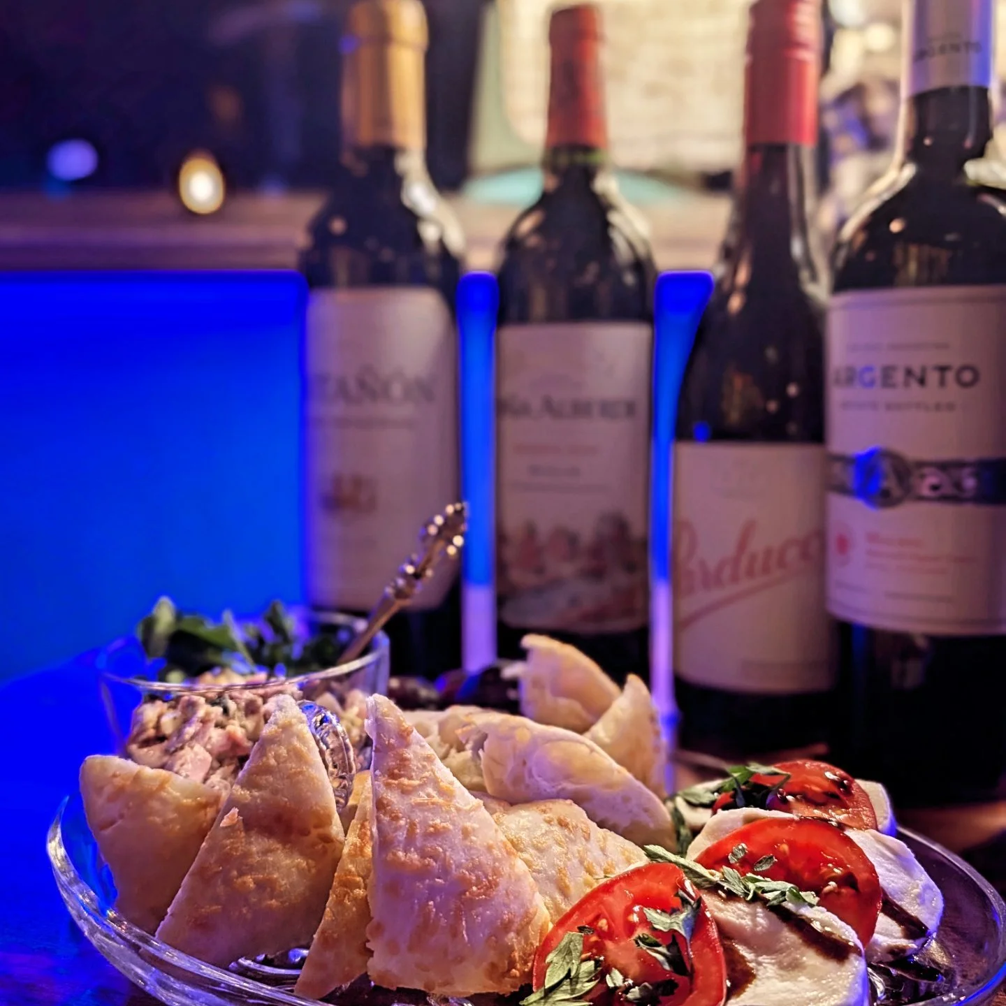 Delectable small plates at Whisperz Speakeasy, set against a backdrop of bottles of Budanero and other exquisite wines.