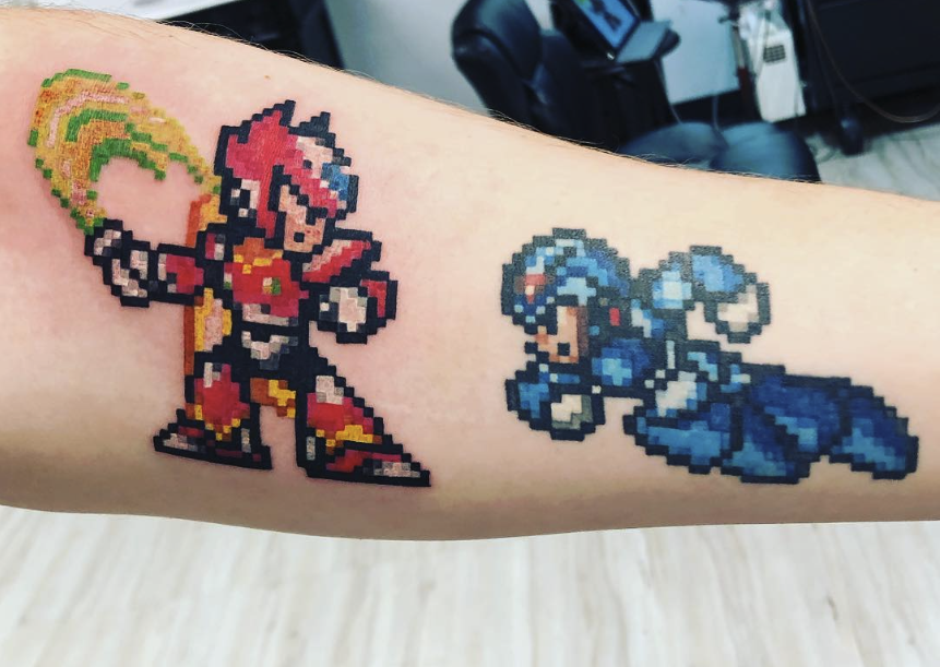 Pixel art tattoo of a red and black armored character holding a rainbow-colored weapon and a blue armored character lying on the ground.
