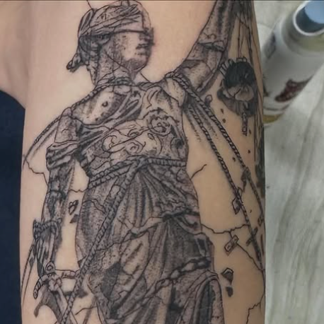 Black and gray tattoo of woman holding the scales of justice