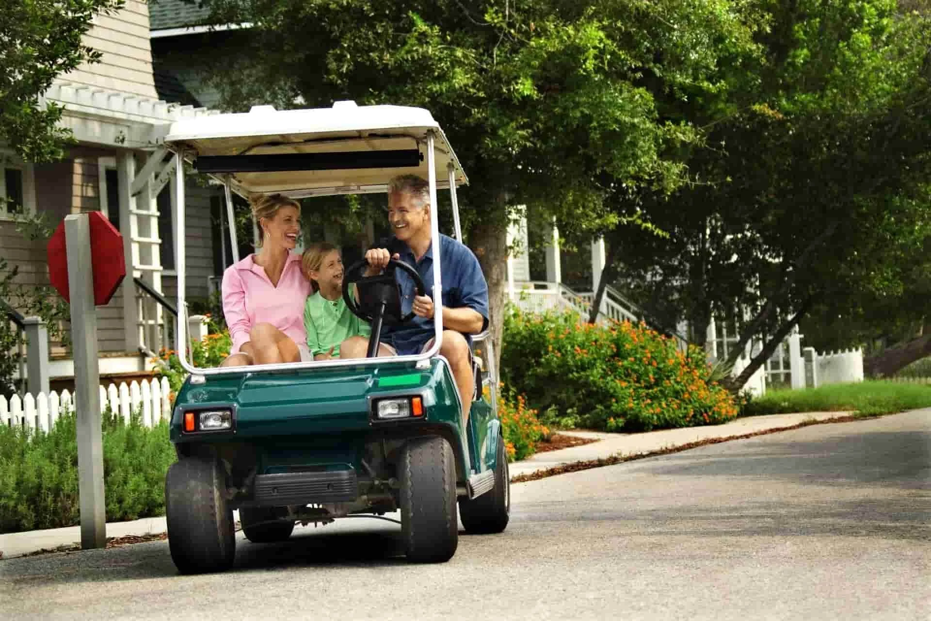 Family riding on a golf cart in a neighborhood with houses behind them