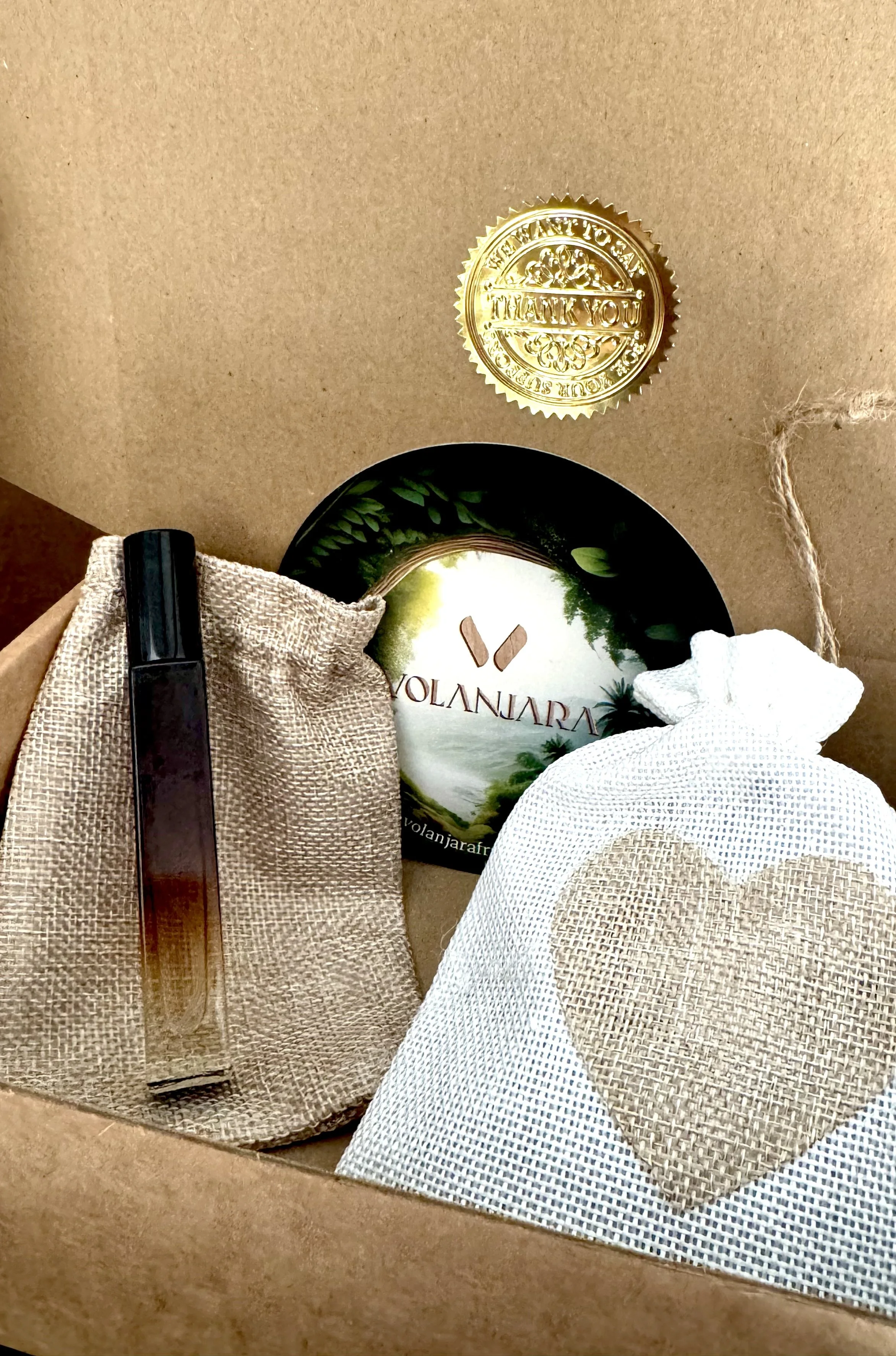 Coffret découverte Volanjara contenant un sachet en toile de jute avec cœur en tissu, un flacon de l'eau de parfum Volanjara 10ml, et un flyer de bienvenue Volanjara, le tout dans une boîte en carton d'expédition