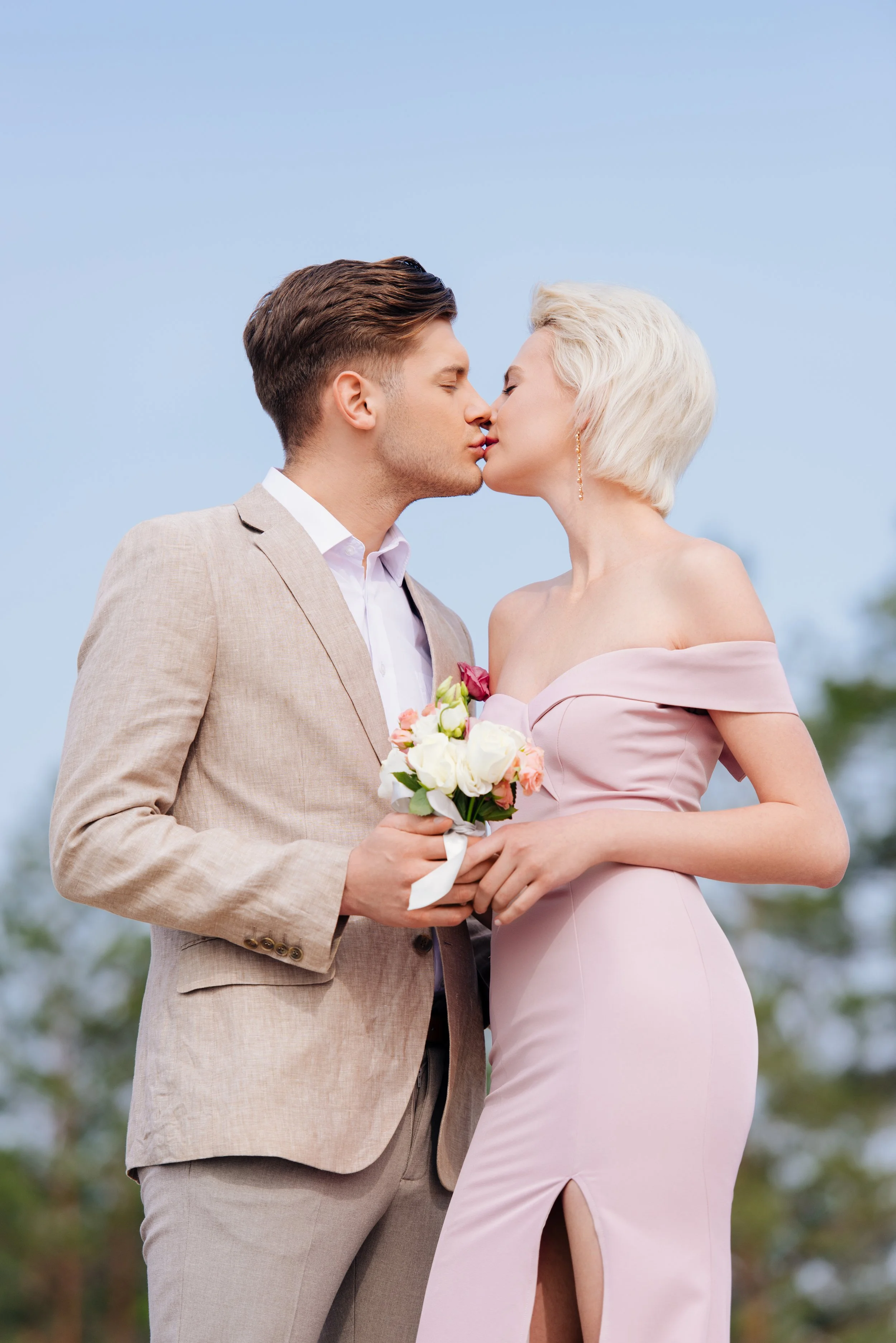 stylish-couple-holding-wedding-bouquet-and-kissing-2023-11-27-05-36-23-utc.jpg