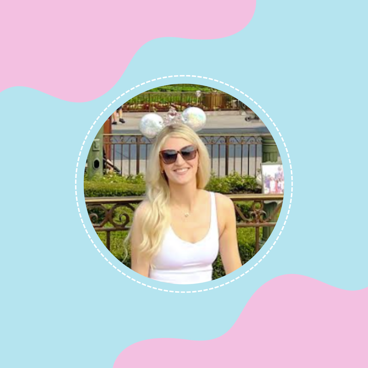 A woman with long blonde hair wearing sunglasses and a white tank top, smiling outdoors with decorative balloons shaped like Mickey Mouse ears in the background.