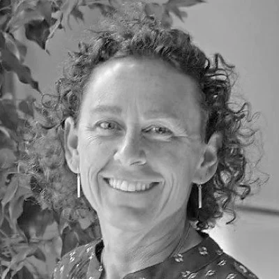 A woman with curly hair smiling at the camera in a black-and-white photo.