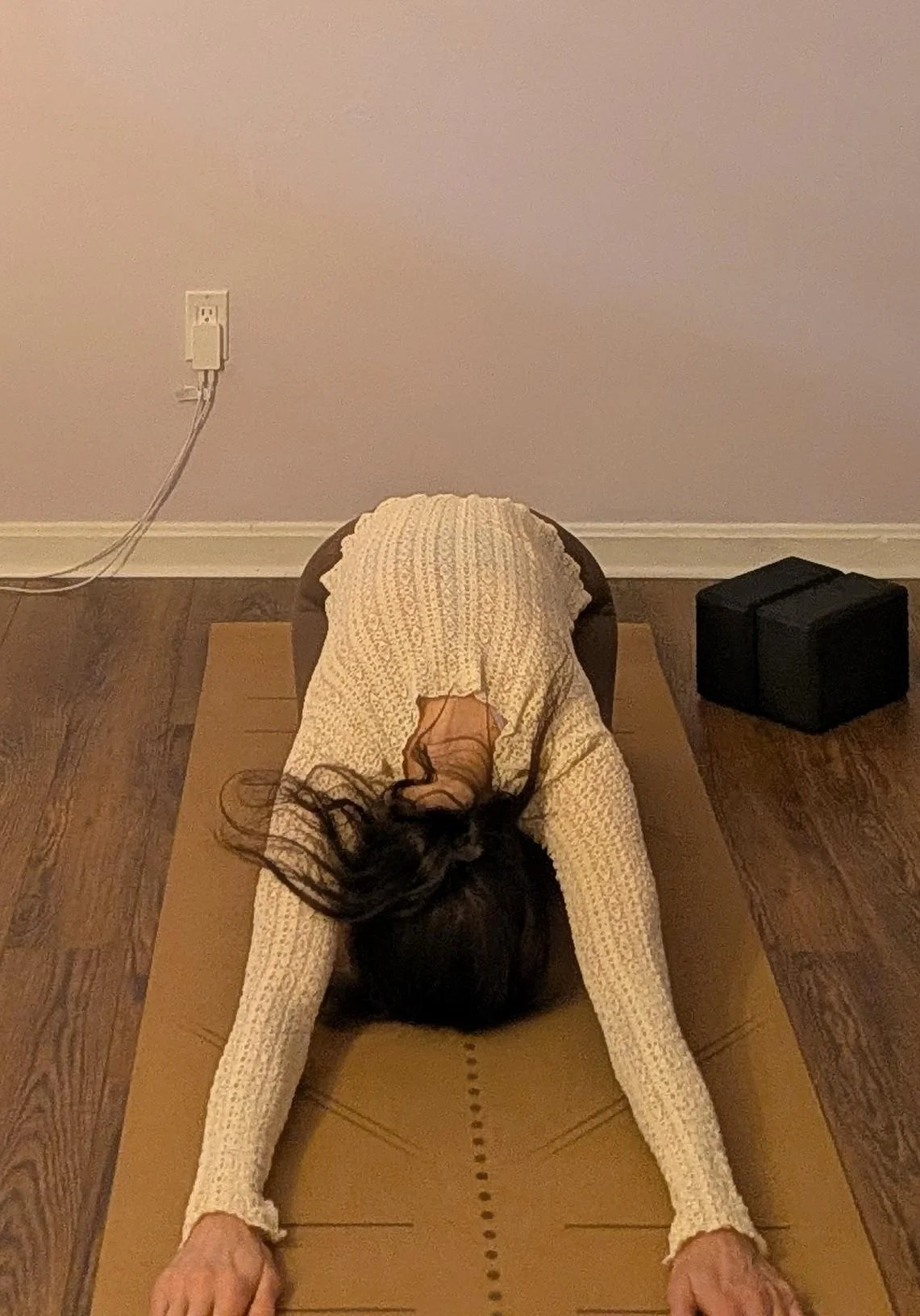 Woman resting in Balasana, child's pose, forehead down and arms extended forward, a shape that asks for nothing more than breath.