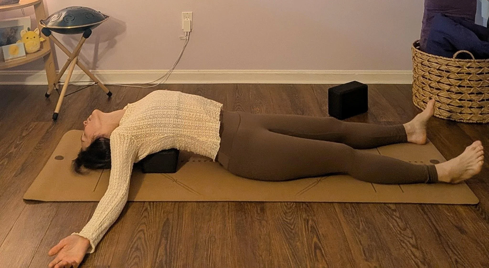 Woman resting in supported heart bench, a gentle backbend opening the chest and heart space with a bolster for support.