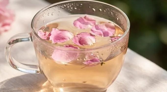 Rose petals steeping in a cup of tea, a cooling ritual for Pitta-style sadness