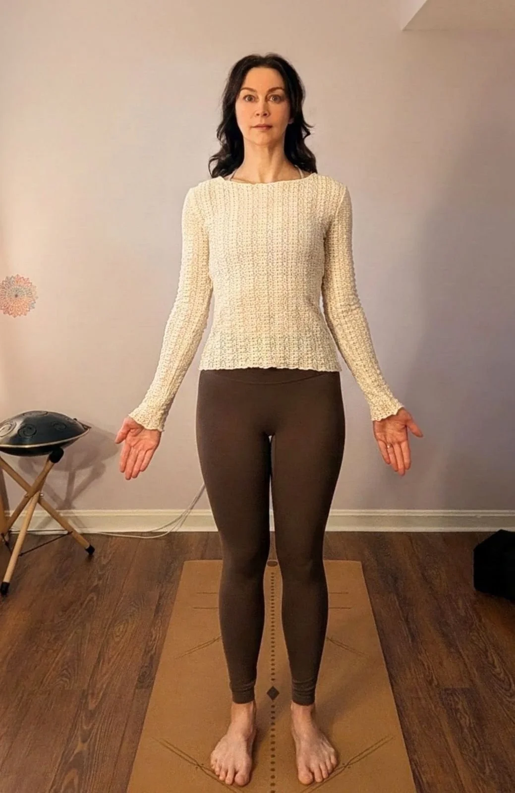 Woman standing in Tadasana, mountain pose, with arms relaxed and feet grounded, representing steady presence as the seasons shift from summer to fall.