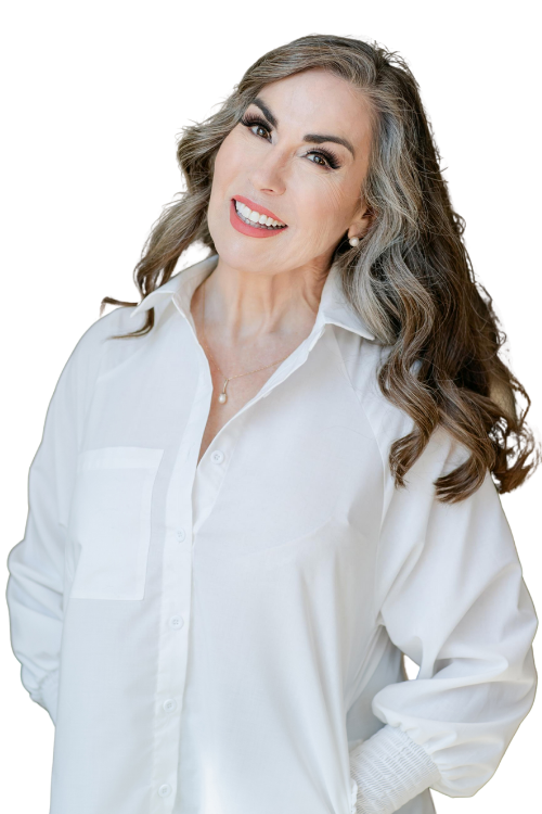A smiling woman with gray, wavy hair wearing a white button-up shirt and pearl necklace, standing against a black background with a small blue section.