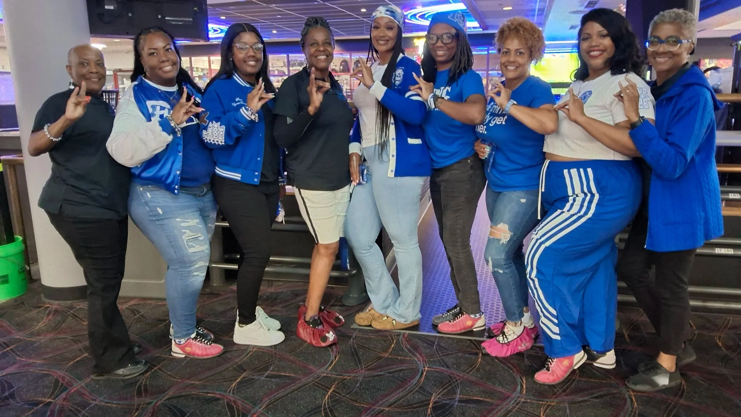 A group of women smiling and posing together at a bowling alley.