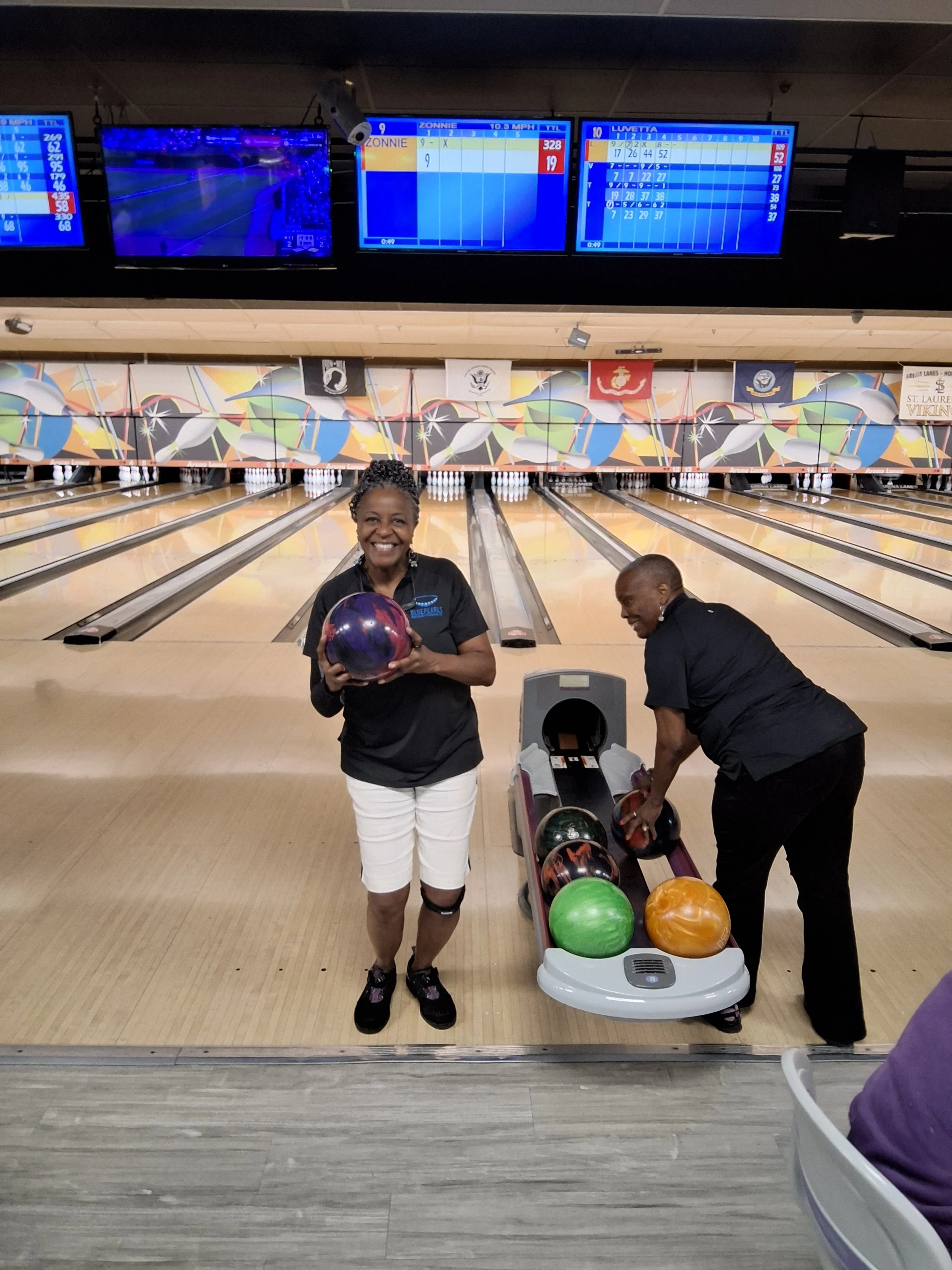 Two women beside the bowling ball rack at BPEFI’s 2026 Bowling for Scholars fundraising event.