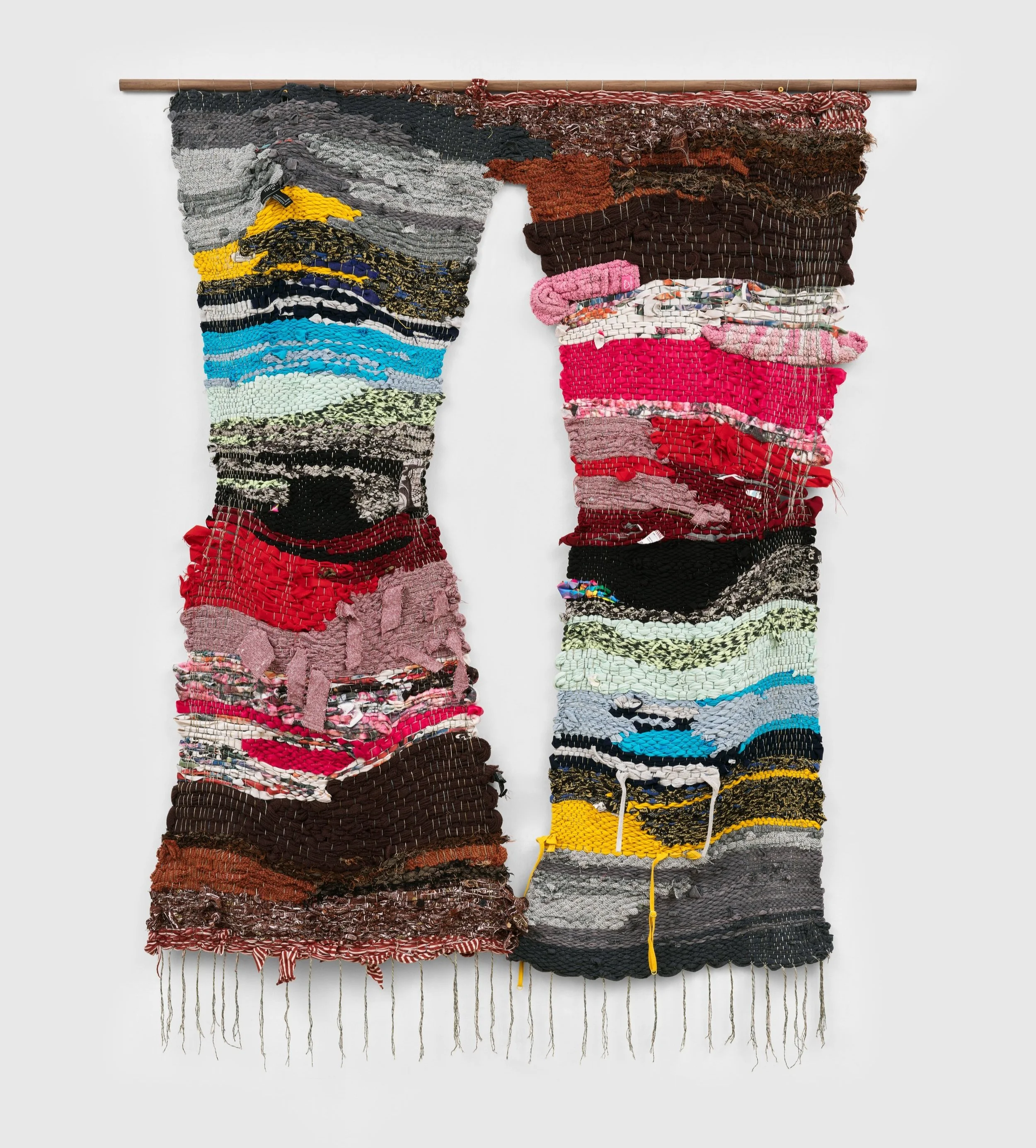 Colorful woven textile art hanging on a wall with various textures and patterns.