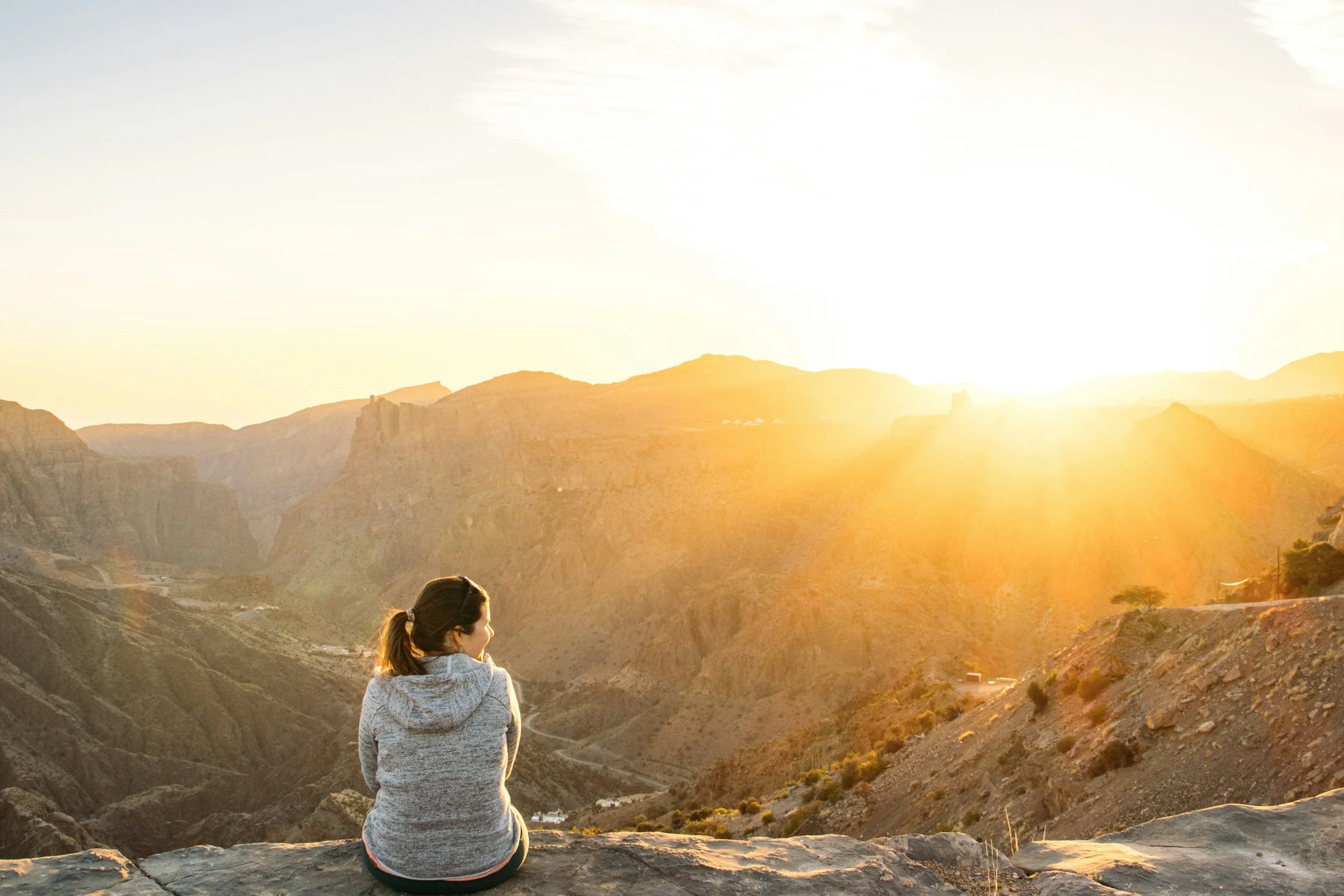 A person sitting on a ridge watching the sunrise over the mountains