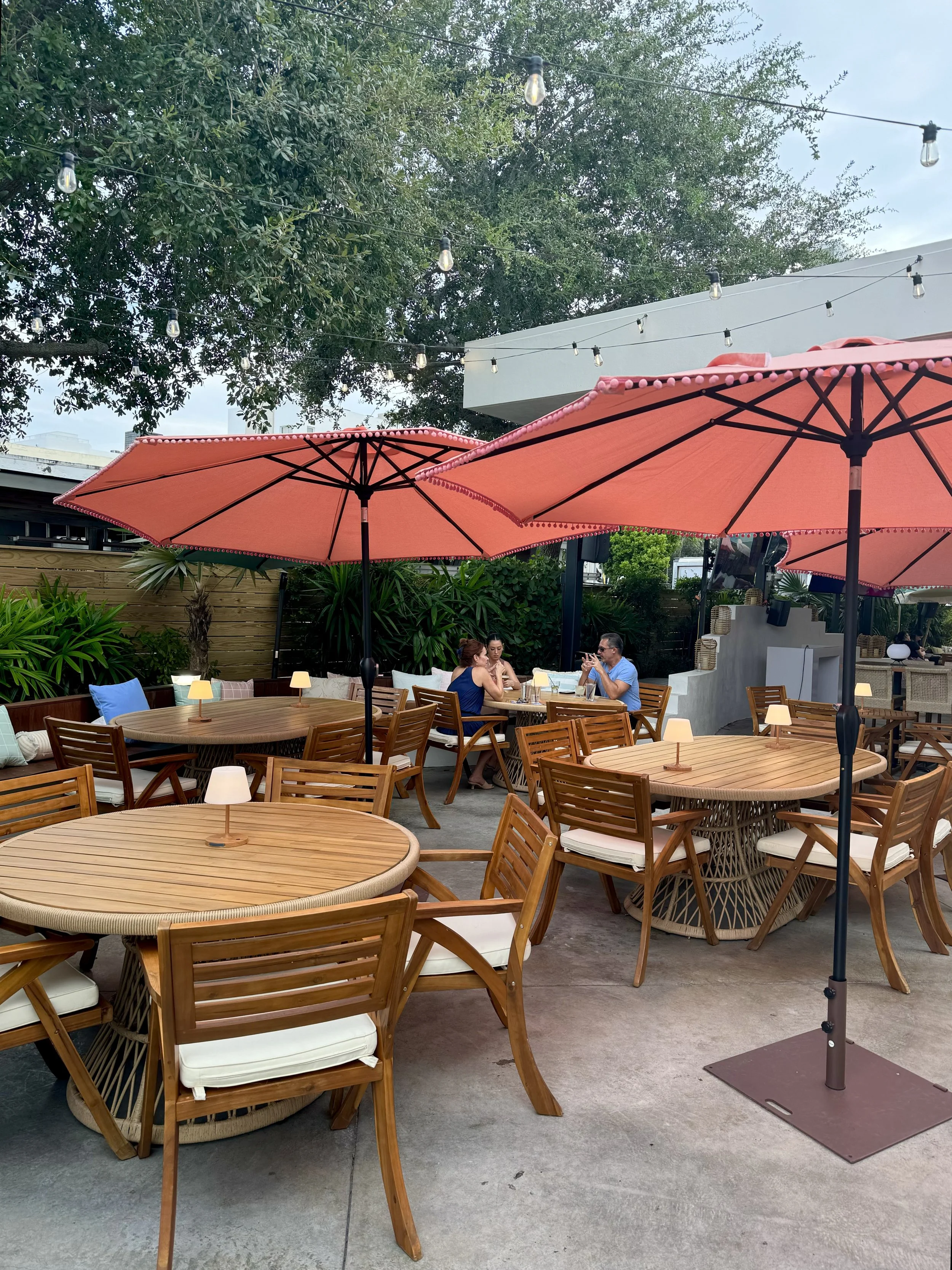 Outdoor patio seating area at Standard Delray Beach restaurant with tables and umbrellas