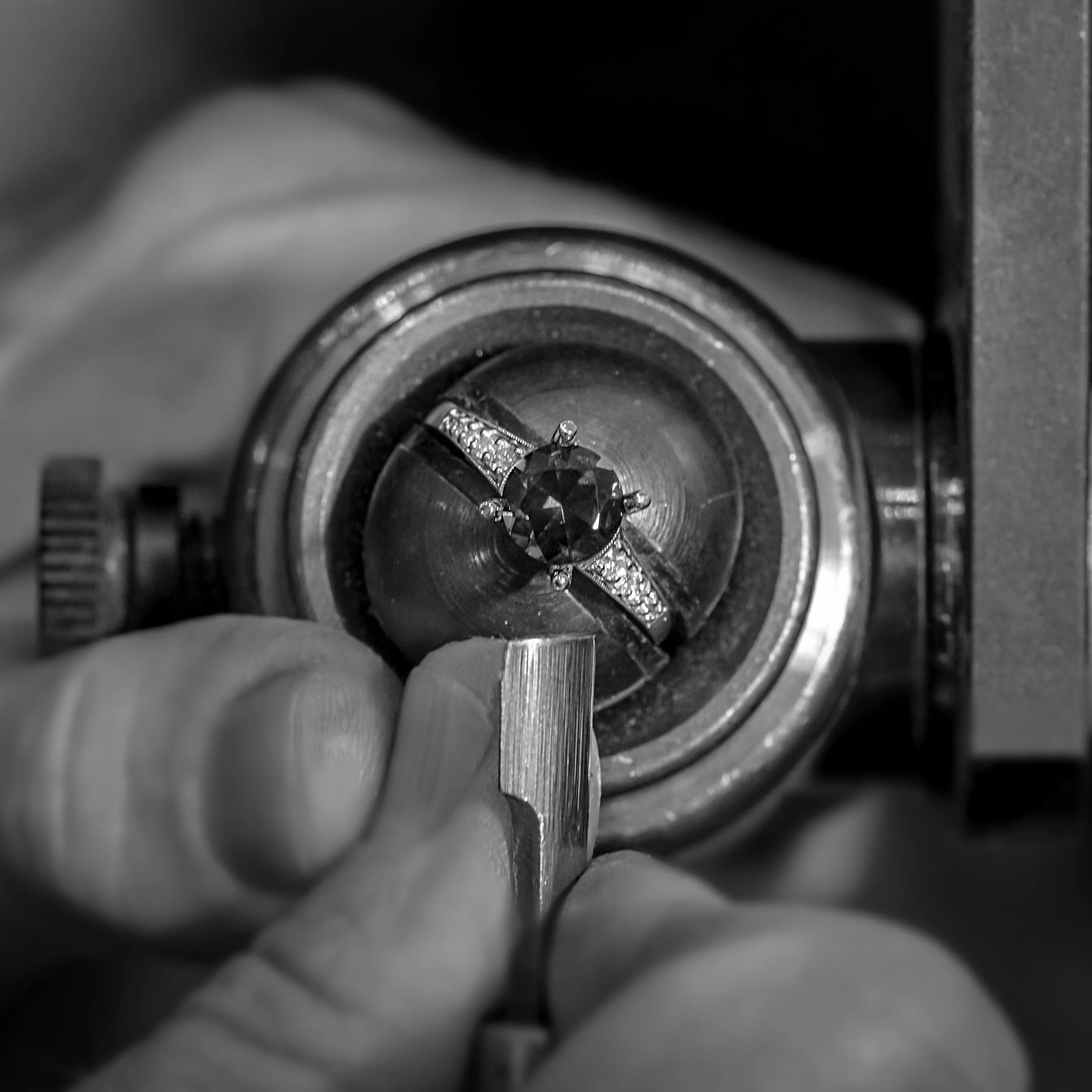 A jeweler setting a black gemstone into a ring during jewelry craftsmanship.