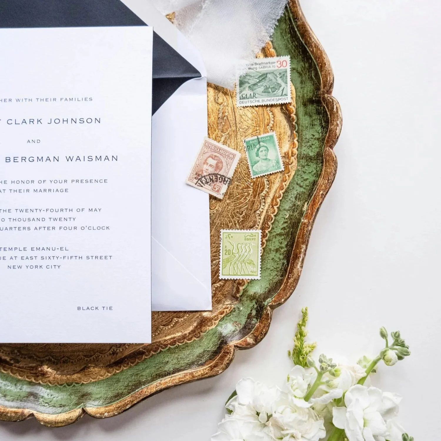Flat lay of a gorgeous wedding invitation, stamps and envelopes
