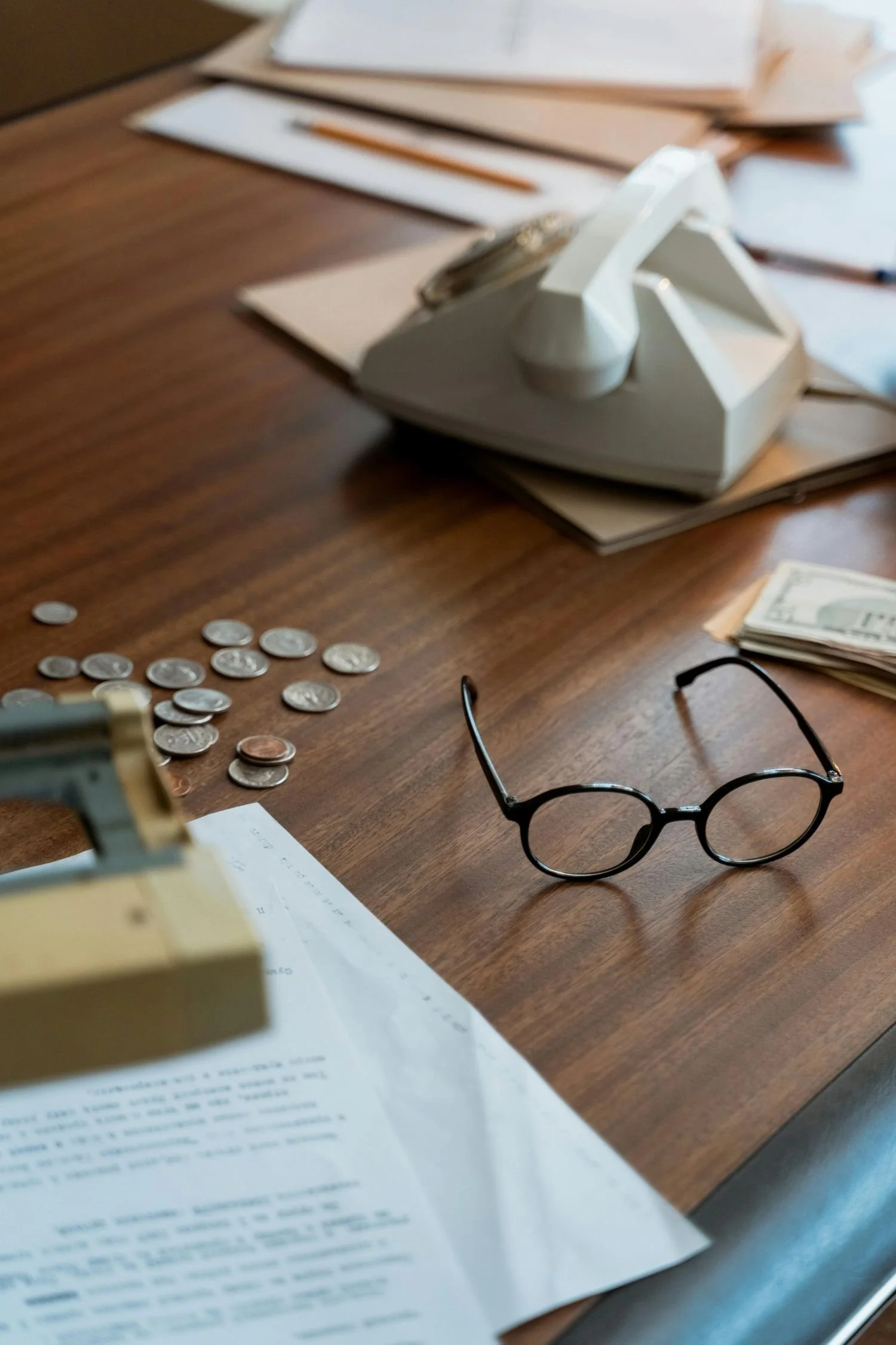 An accountant's desk with a phoen, glasses and money
