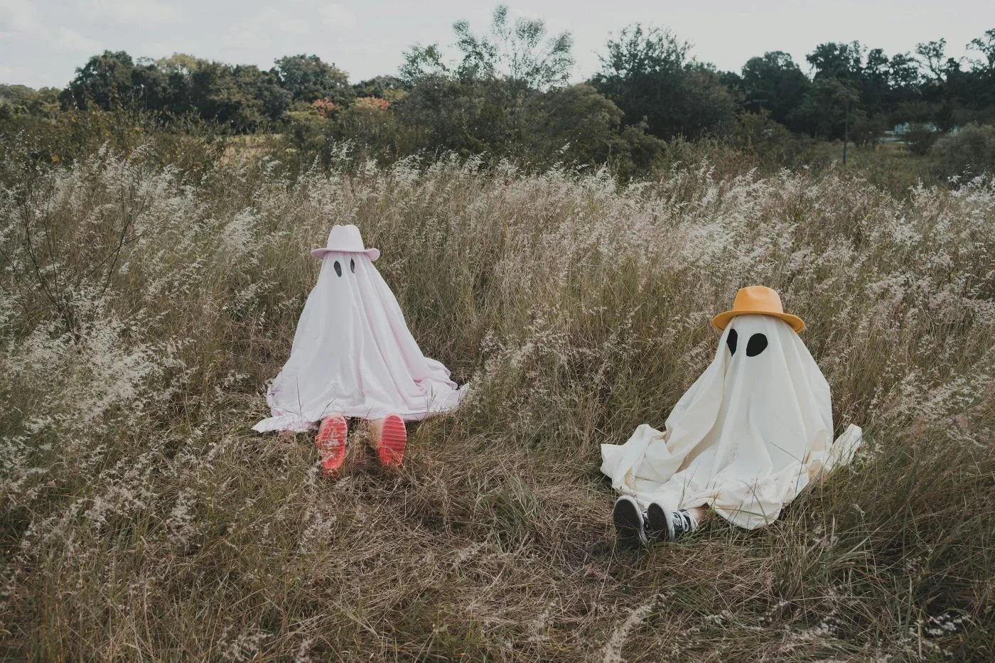 A couple dressed as ghosts sitting in a field