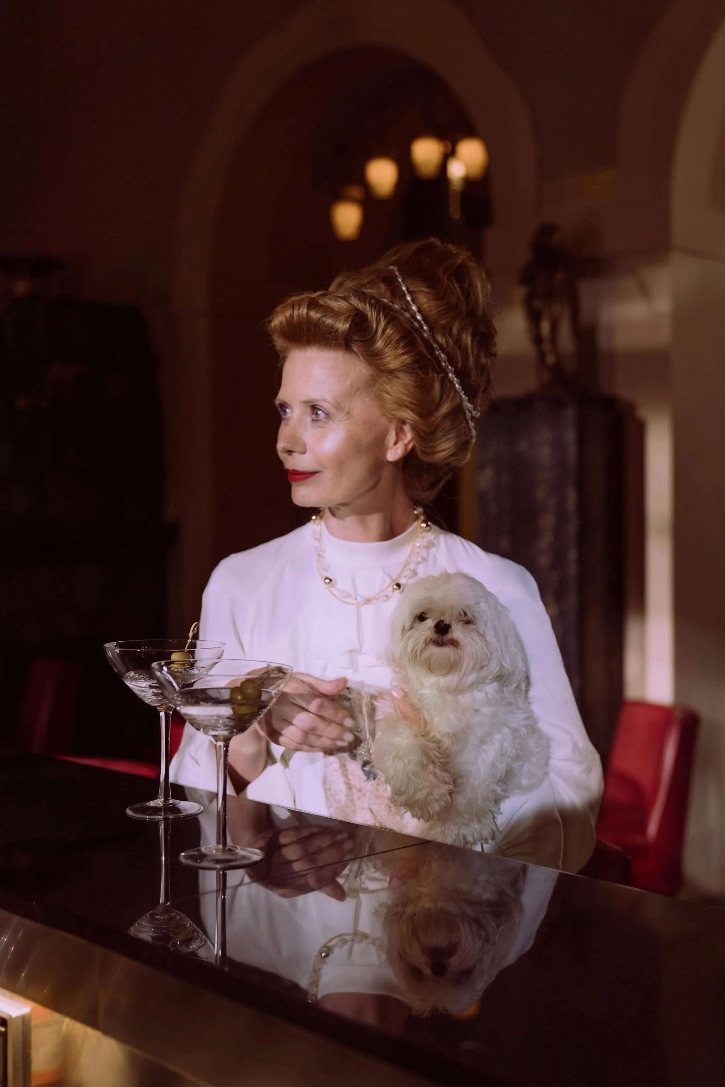 Woman at a bar with two martinis and a small dog