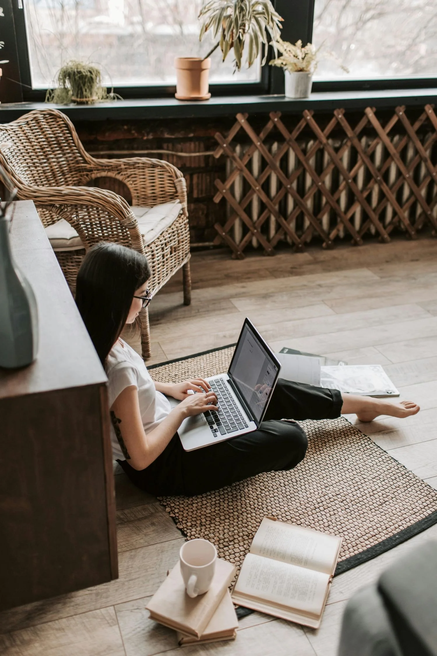 A woman sitting on the floor with her laptop learning how to use Squarespace