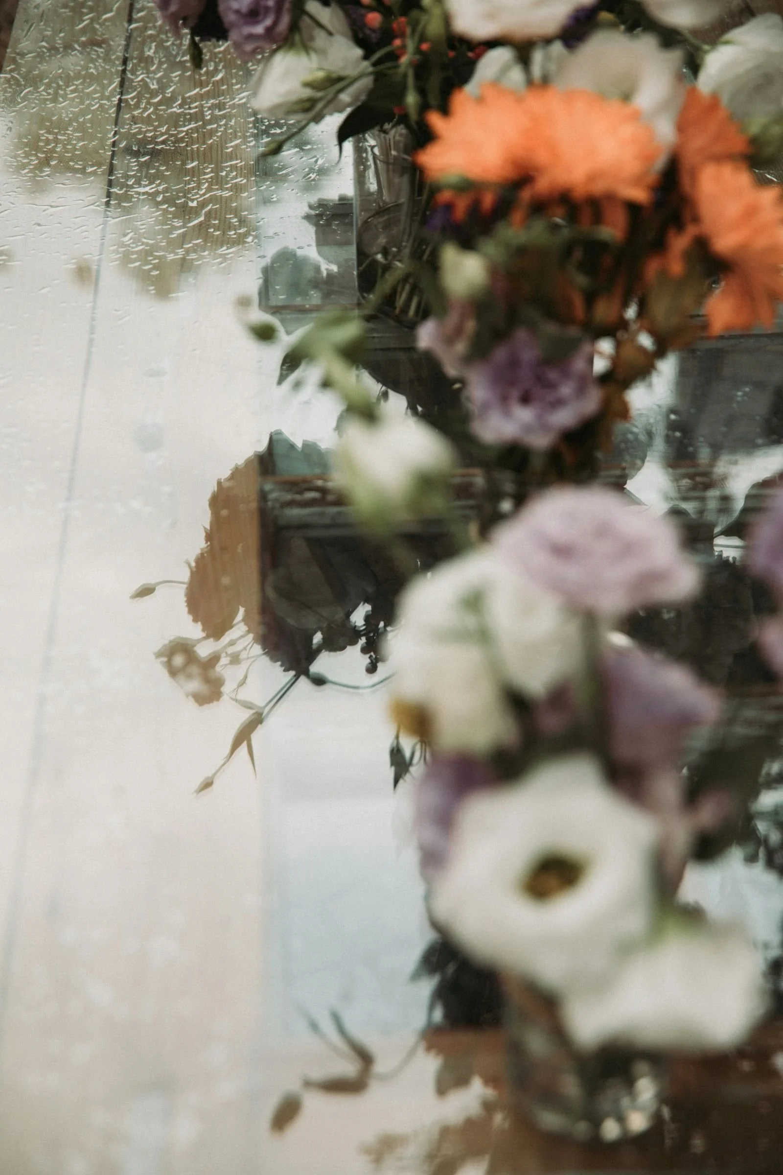 Blurry flowers next to a window with rain