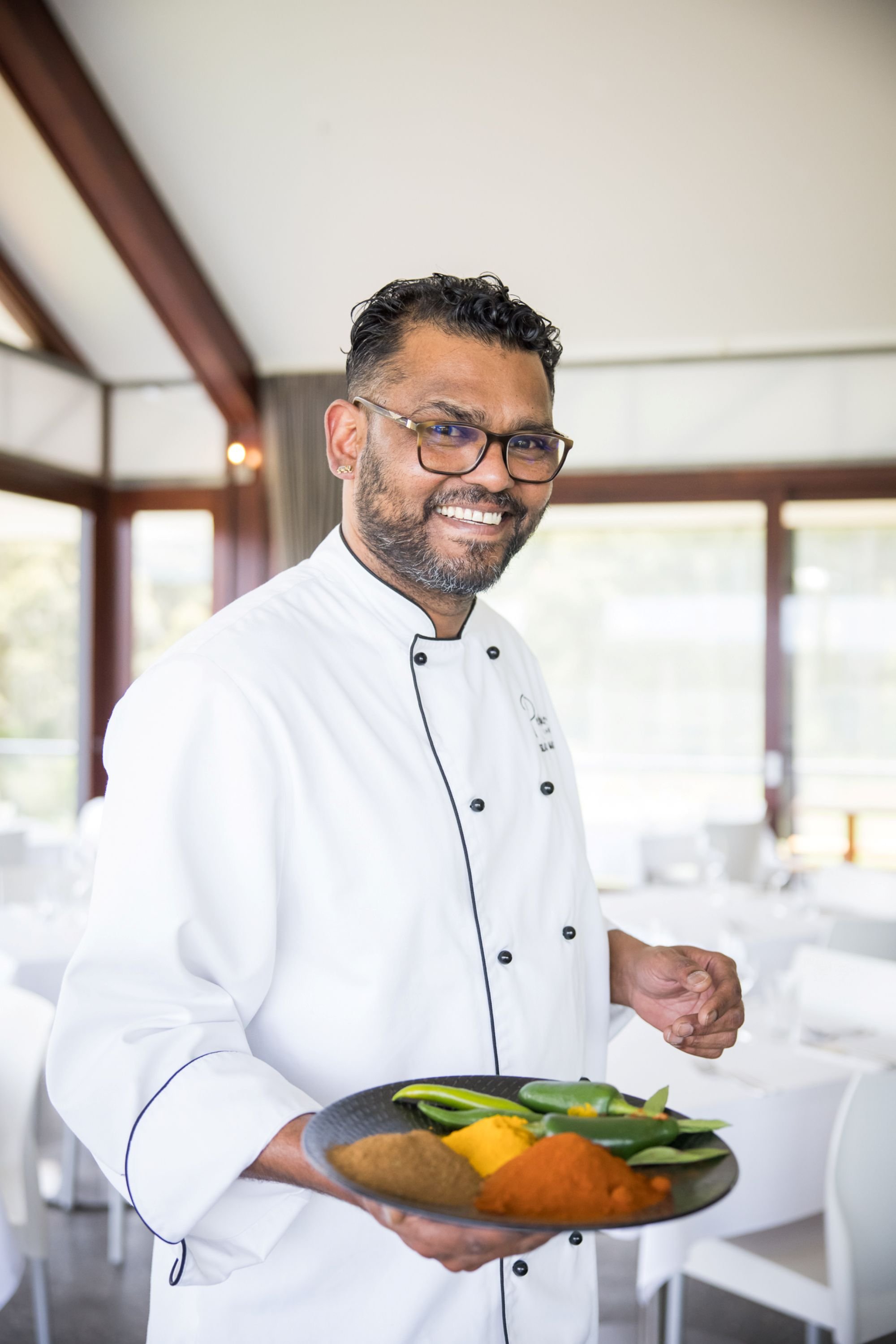 Wedding Caterer Silas Masih standing in his venue with a plate of spices