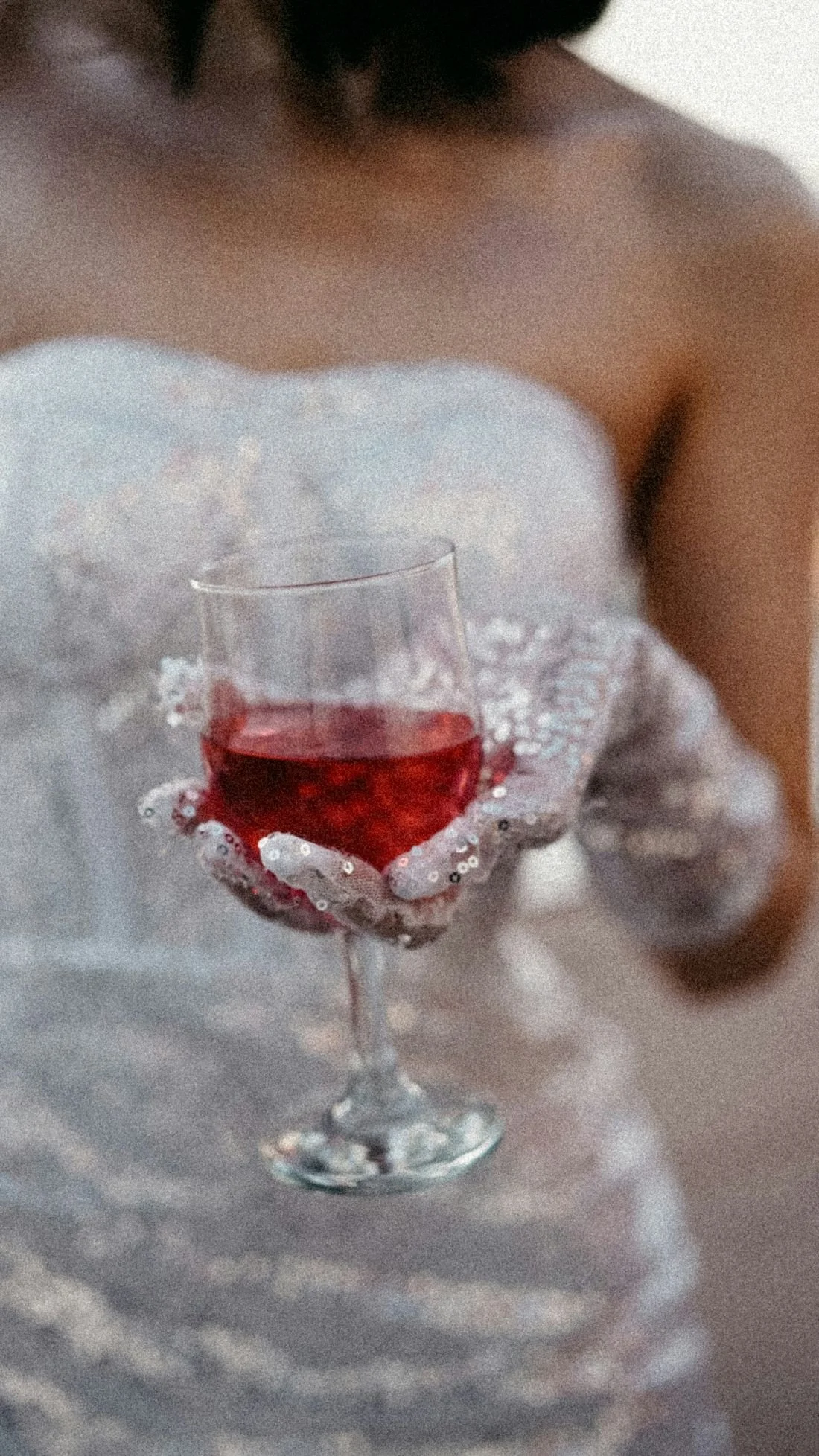 A bride in sequin gloves holding a glass of wine