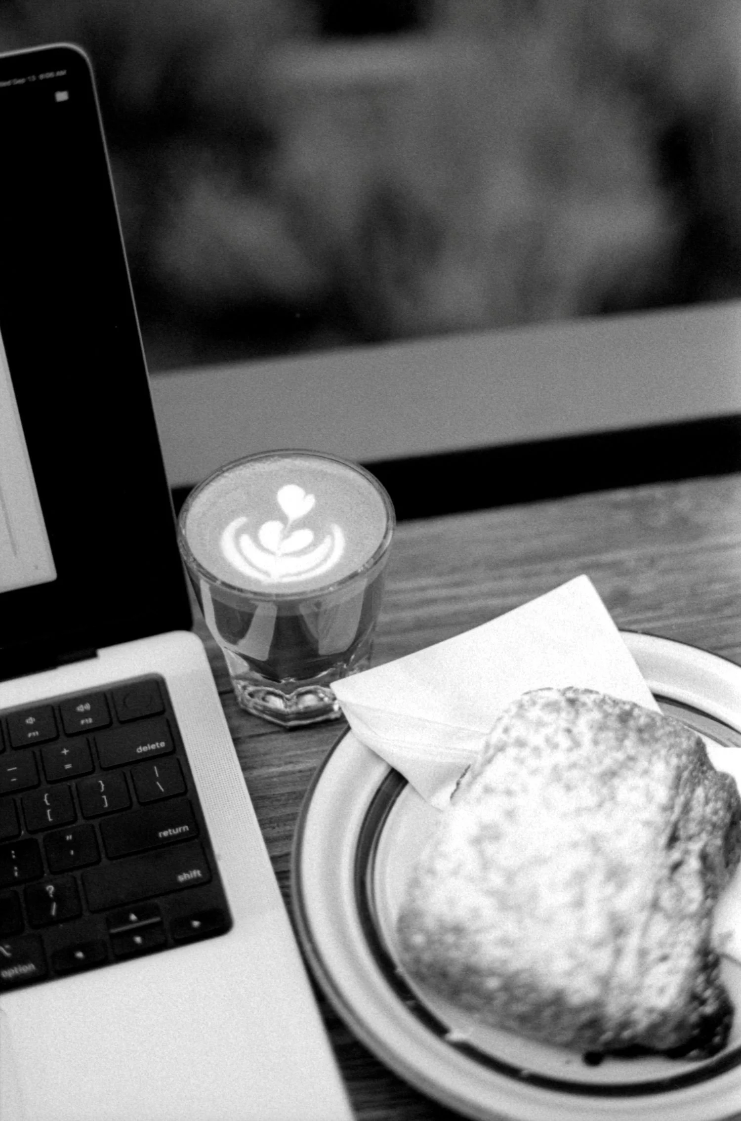 A laptop next to coffee and a pastry