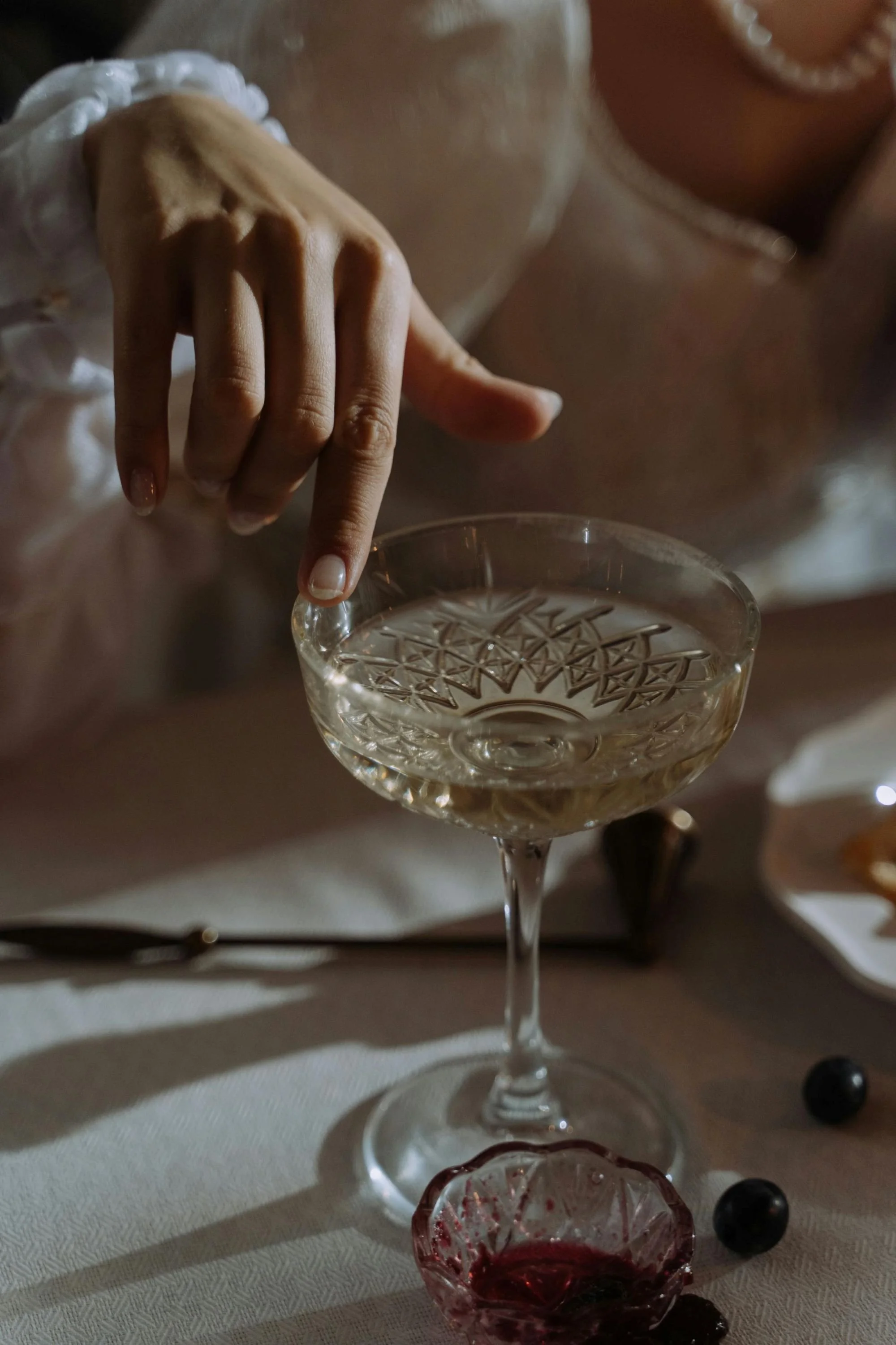 A bride touching the rim of a crystal champagne coupe