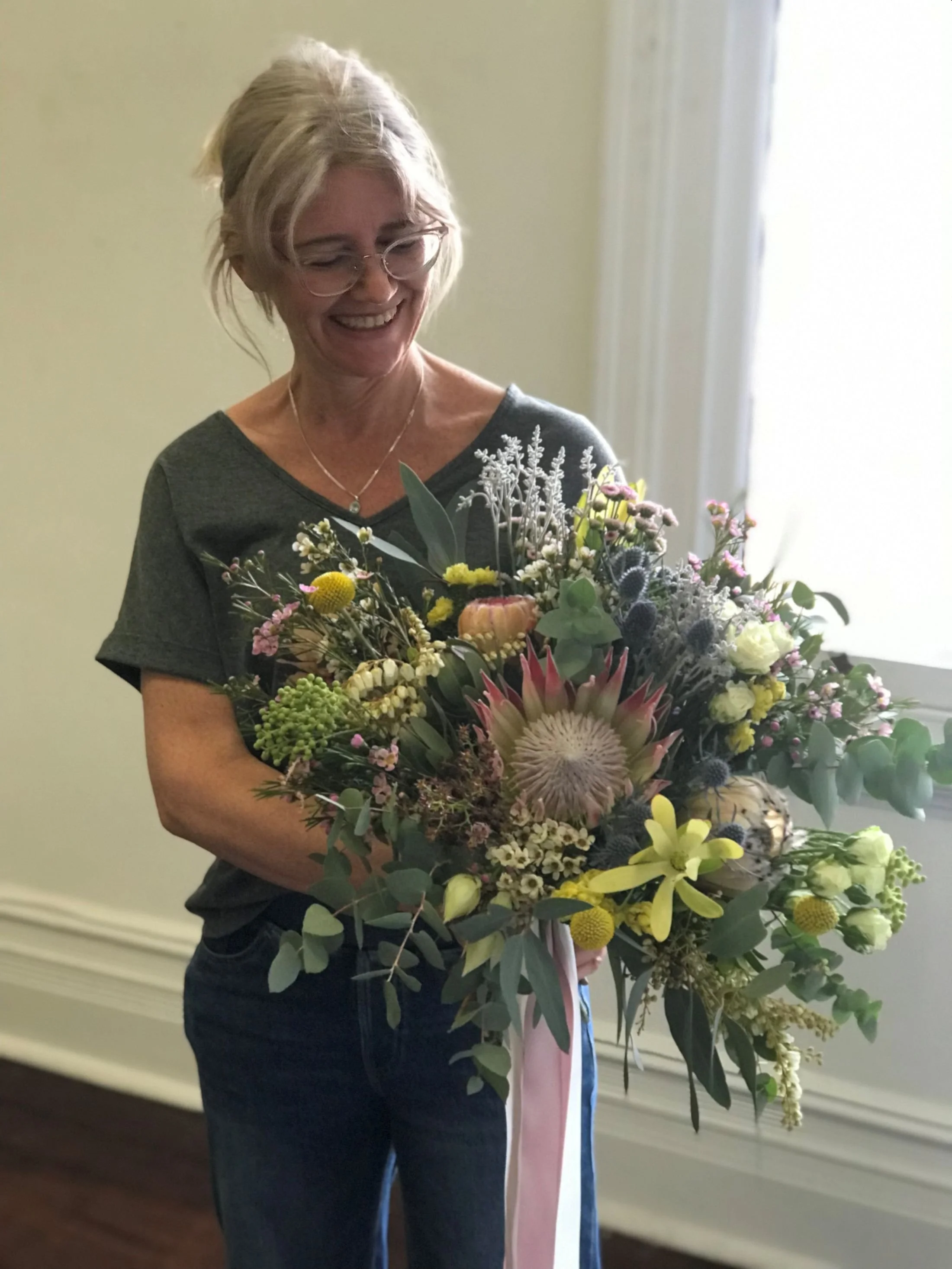 Wedding florist Sandra Madeo smiling holding a large bouquet of flowers