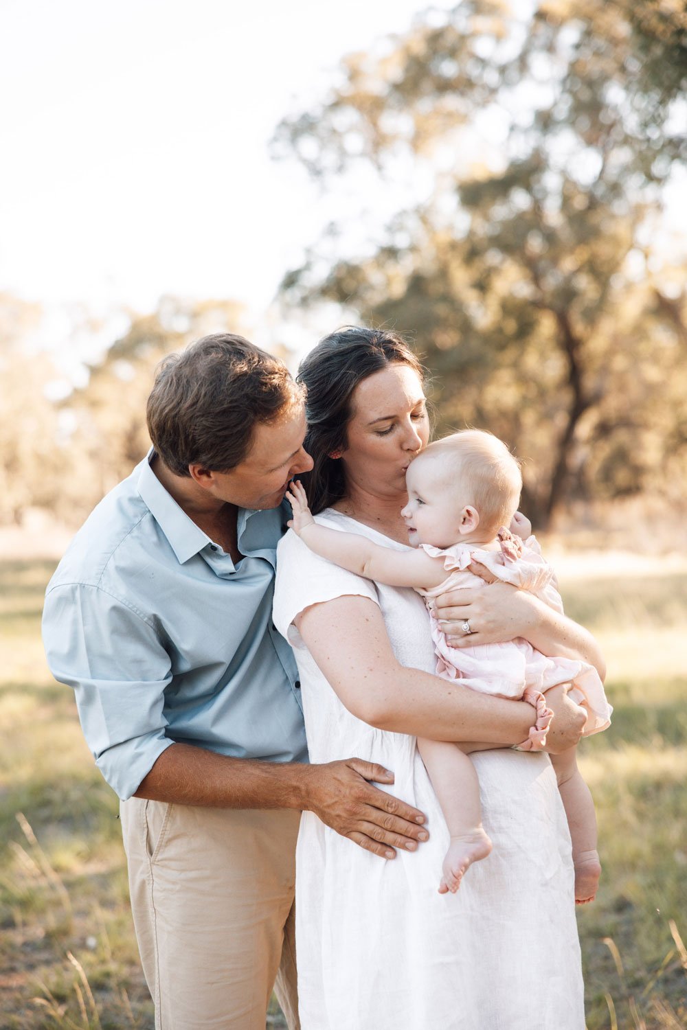 Young couple kissing and looking fondly at their baby