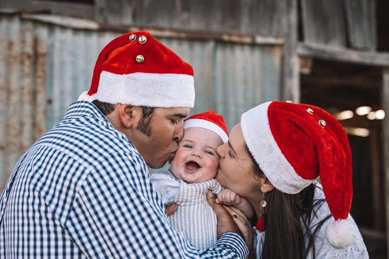 Young couple with happy toddler wearing santa hats for a Christmas card