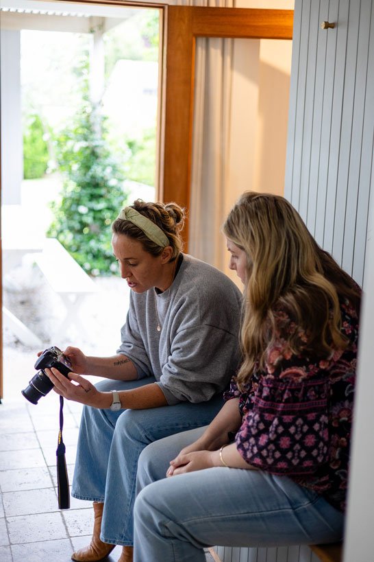 A photographer instructor sitting on a bench teaching a studio how to use a camera