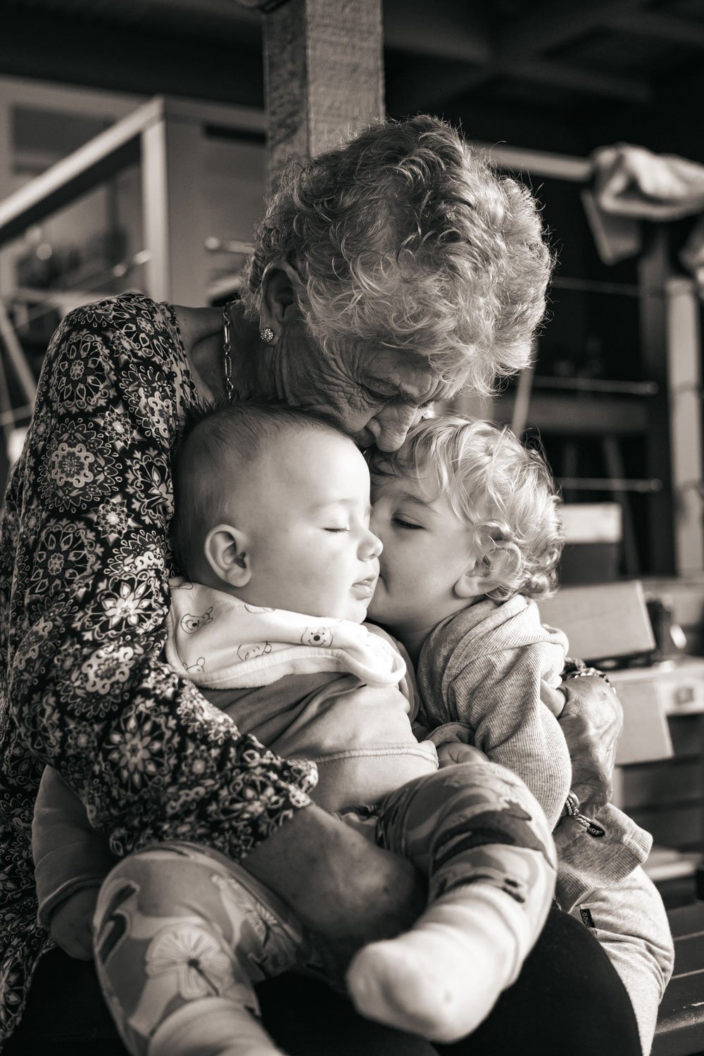 Black and white photo of a great grandmother cuddling her two baby great-grandchildren