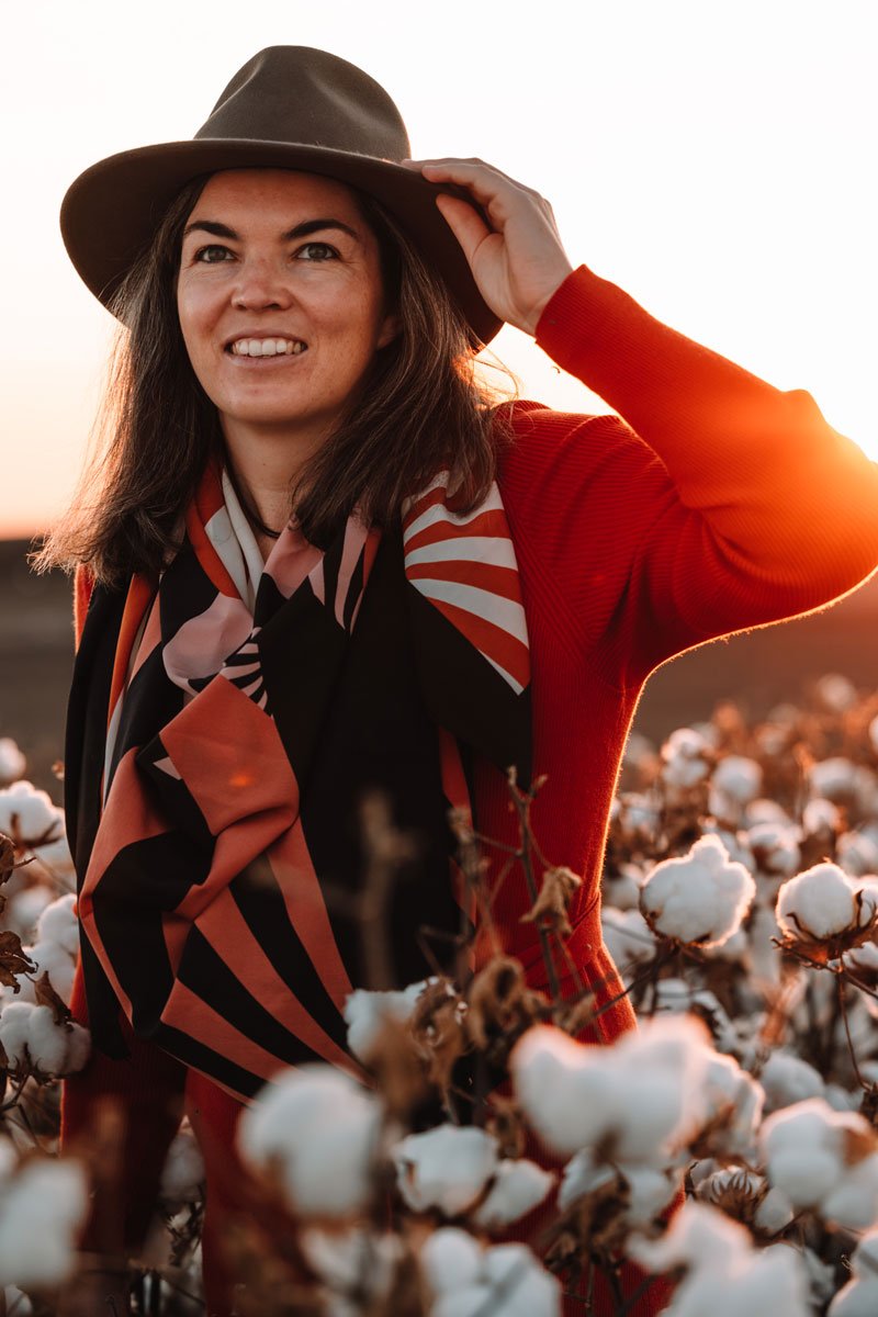 Woman in a cotton field wearing akubra hat with sunset in the background