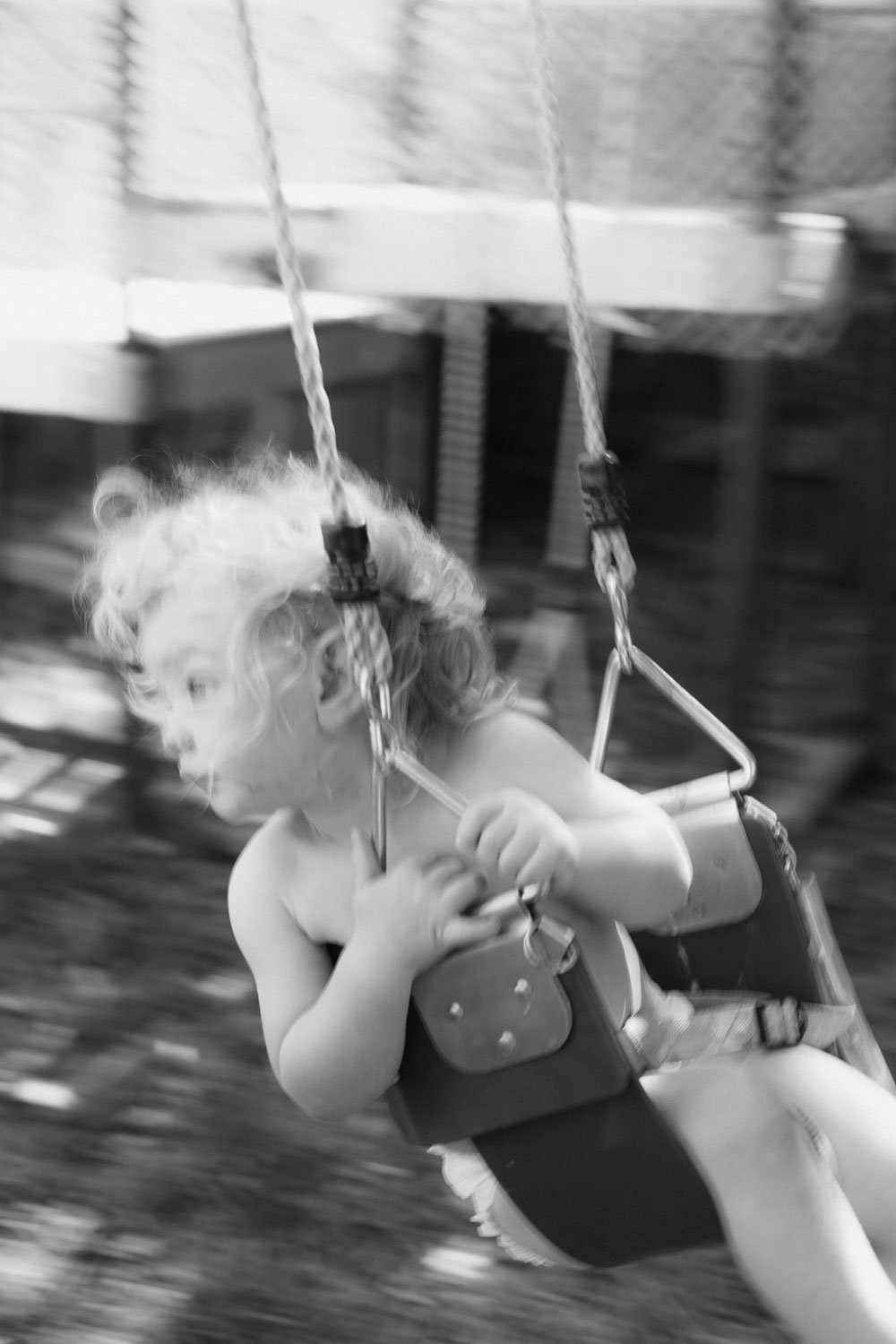 Black and white photo of a boy toddler in a swing