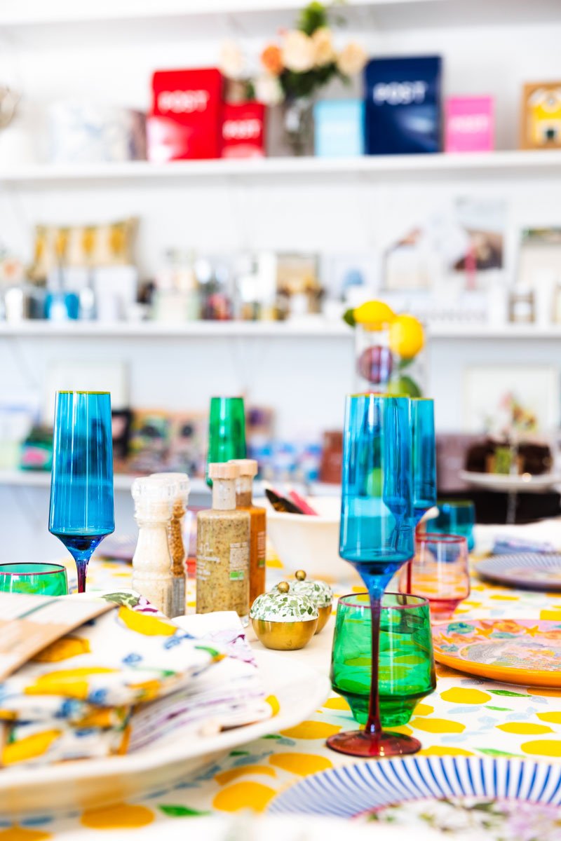 A table of brightly coloured homewares including tableware and knick knacks in a rural shop
