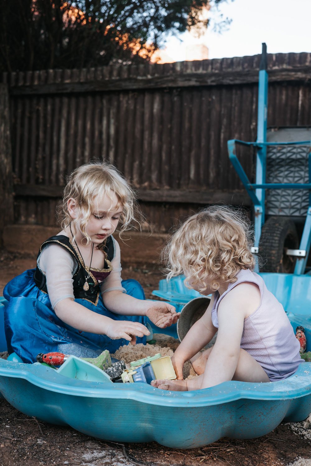 Brother and sister playing in a blue shell sandpit