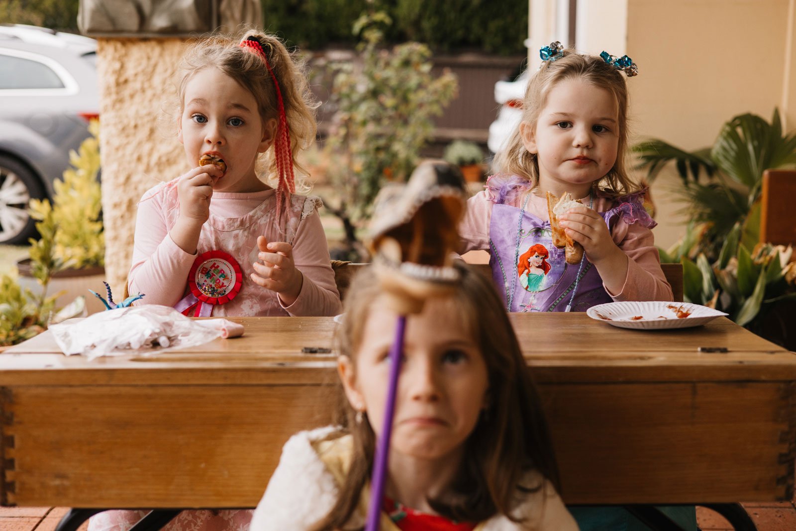 Three young girls playing and eating at an old school desk