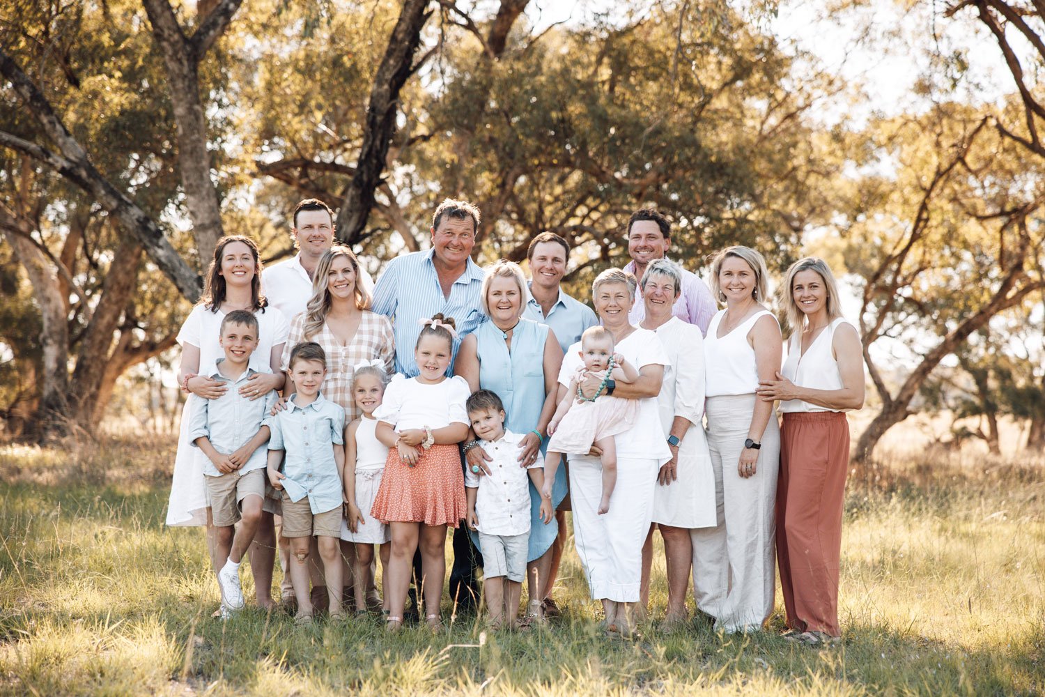 Big family with babies, young children, older children and grandparents smiling at the camera