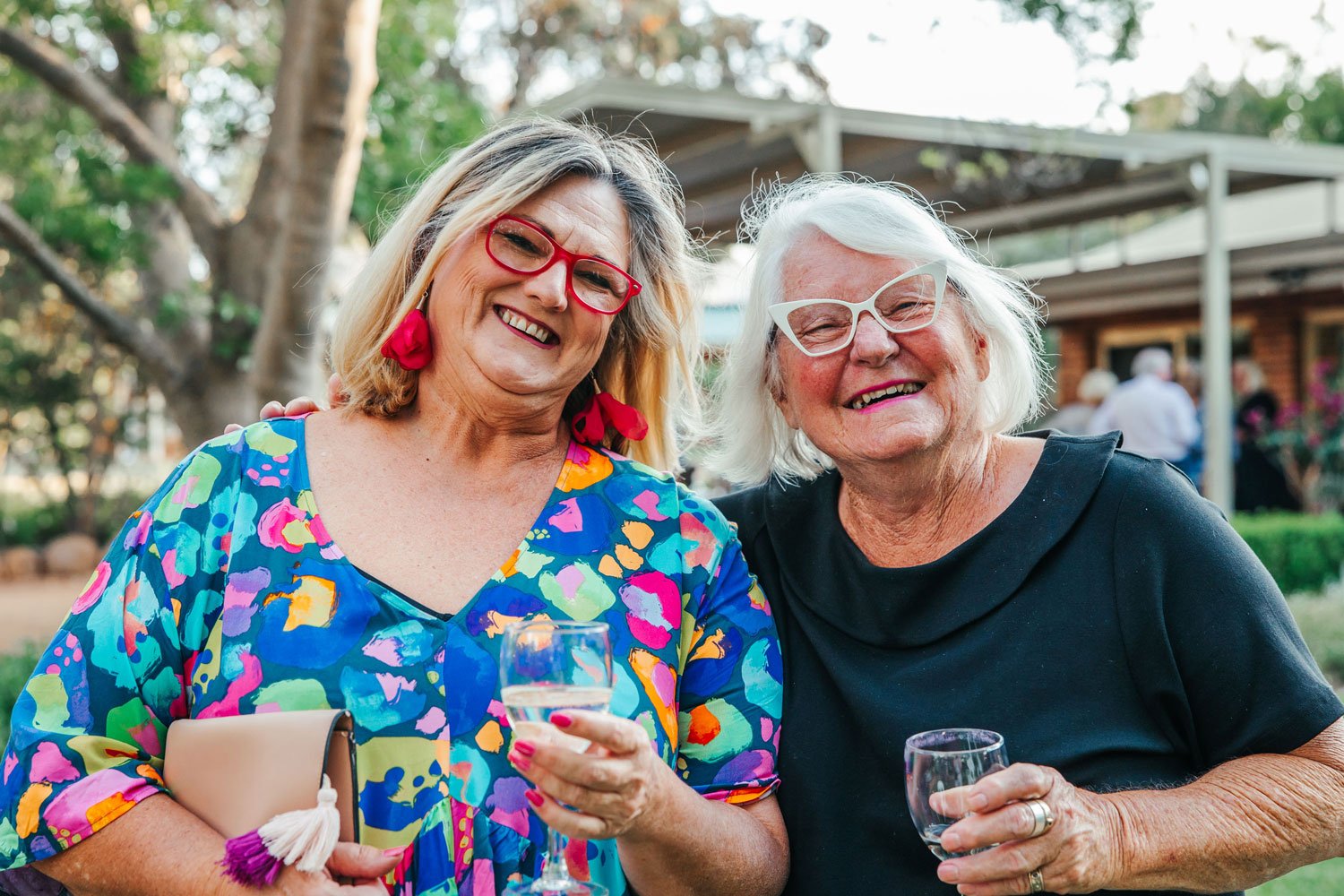 Two women in bright dresses smiling at an event