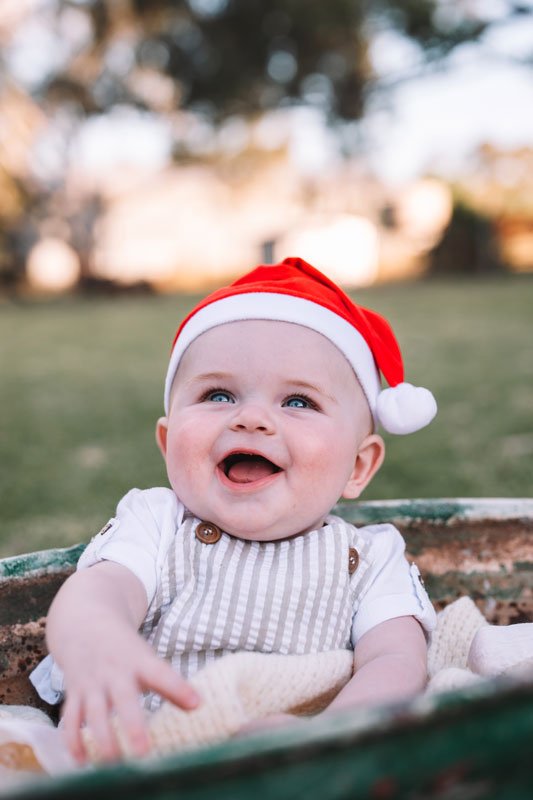 Toddler boy laughing with a santa hat on for Christmas