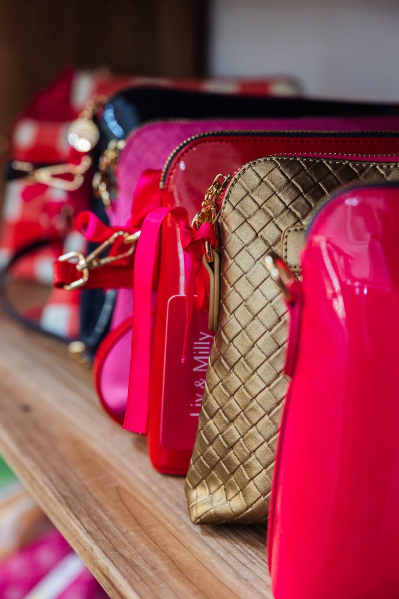 A row of brightly coloured clutch handbags on a shelf