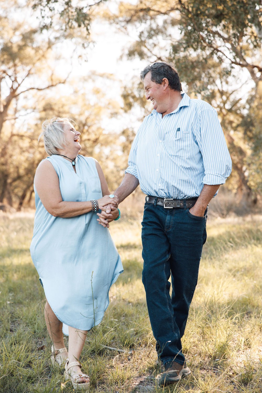 Older farmer and woman smiling and laughing, holding hands