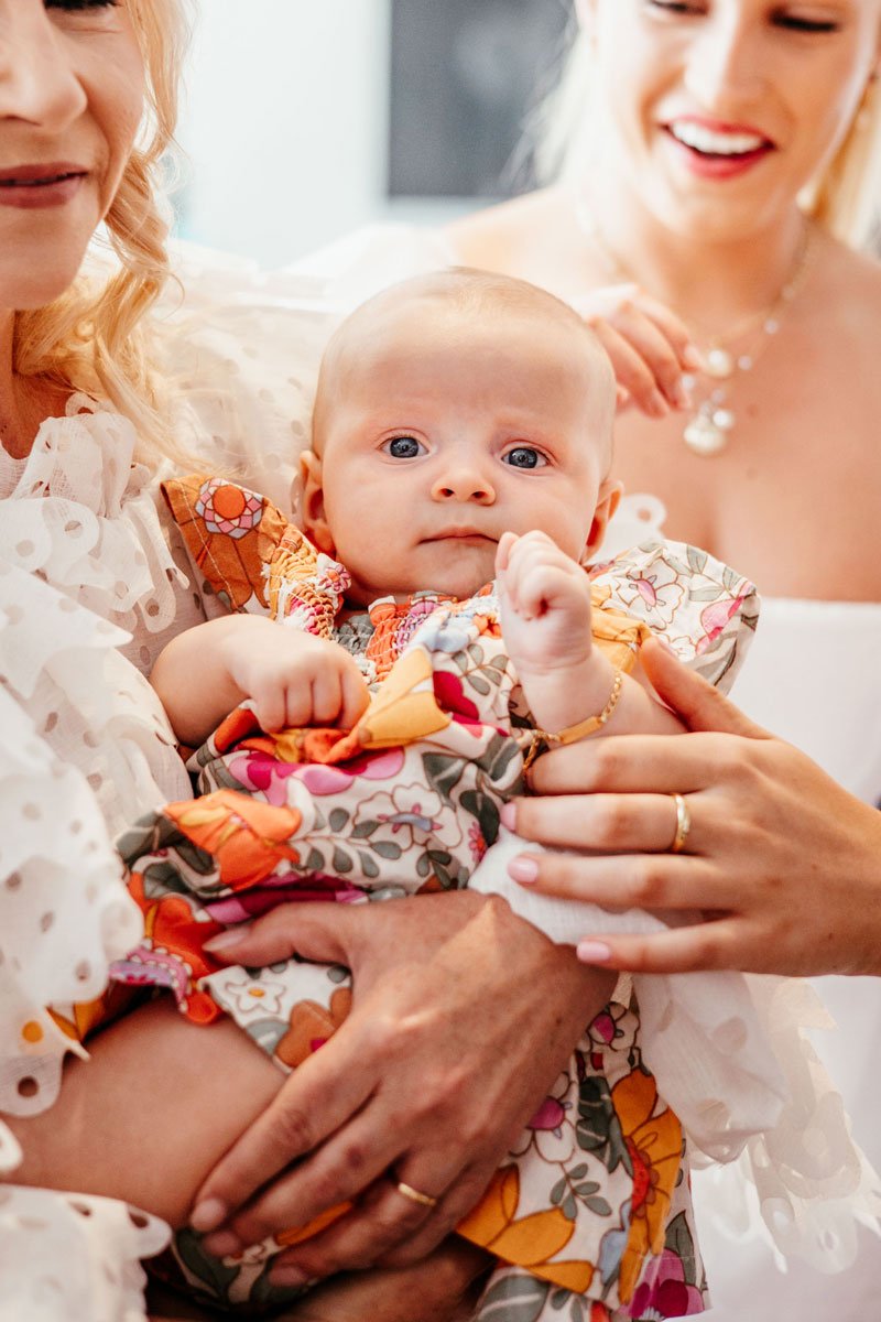 Close up of two women holding young baby looking straight at the camera