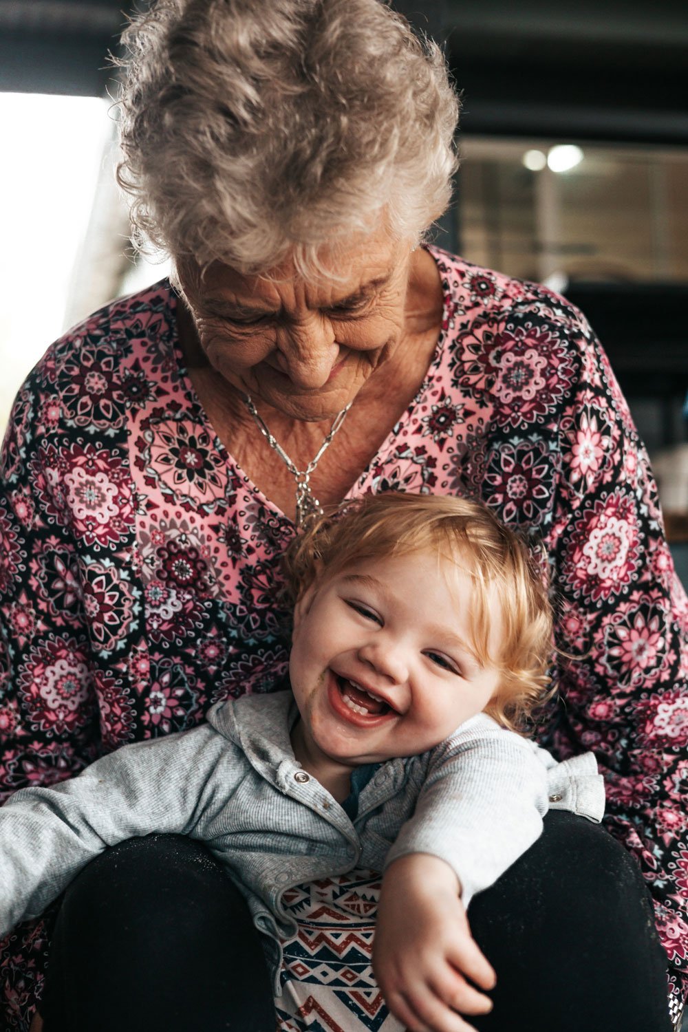 Great grandmother smiling down at her laughing great-grandson