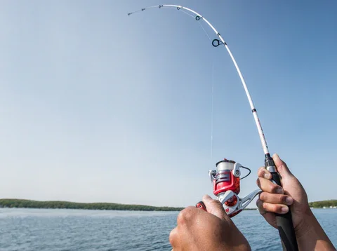 Person holding a fishing rod by the water, preparing to fish.