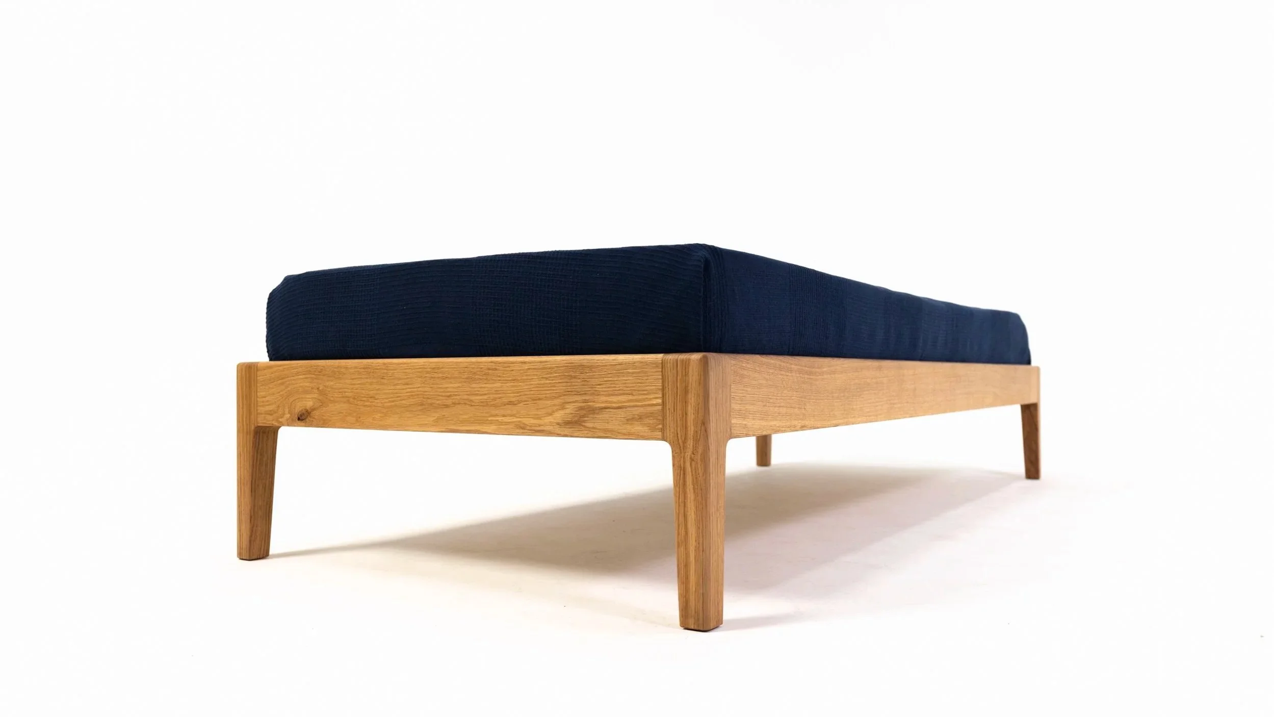 Schlichtes Designerbett aus massiver Eiche im Schlafzimmer, reduziertes Design ohne Kopfteil