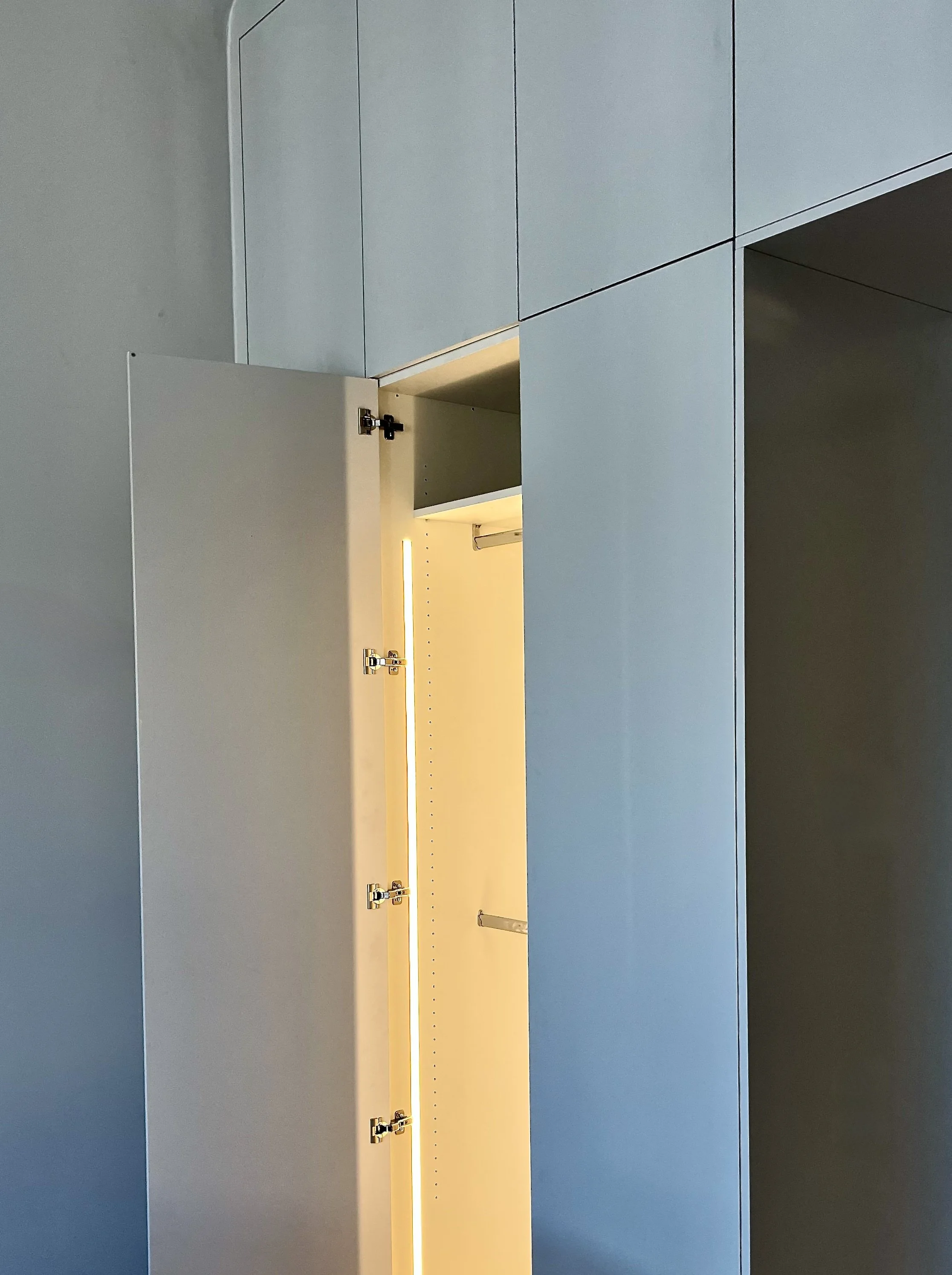 Offene graue Schublade in einer modernen, blauen Schrank- oder Möbelwand mit Beleuchtung innen.